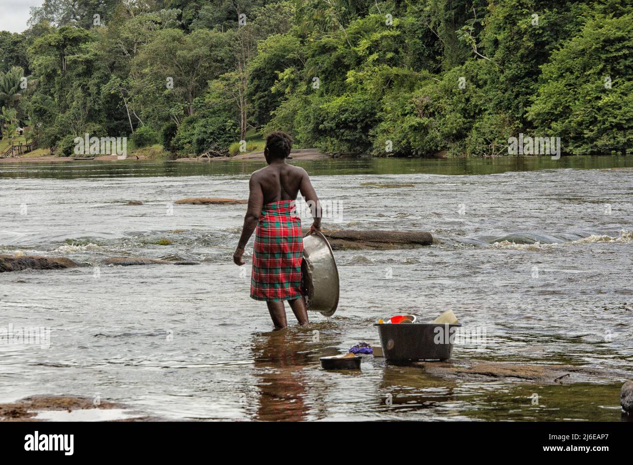 Donna che sbatte piatti nel fiume in Suriname Foto Stock