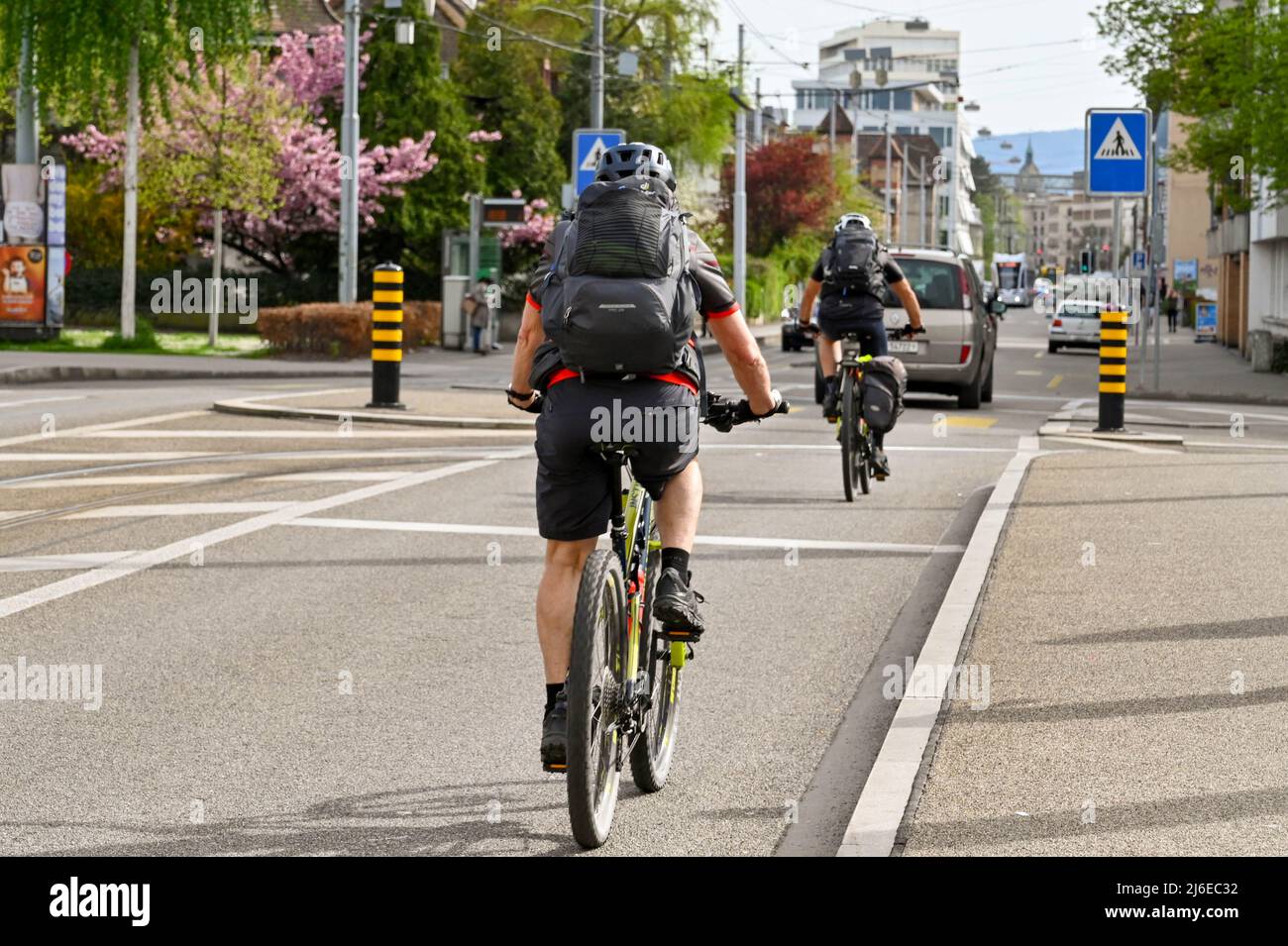 Basilea, Svizzera - Aprile 2022: Le persone che pedalano a casa dal lavoro in una strada alla periferia del centro della città Foto Stock