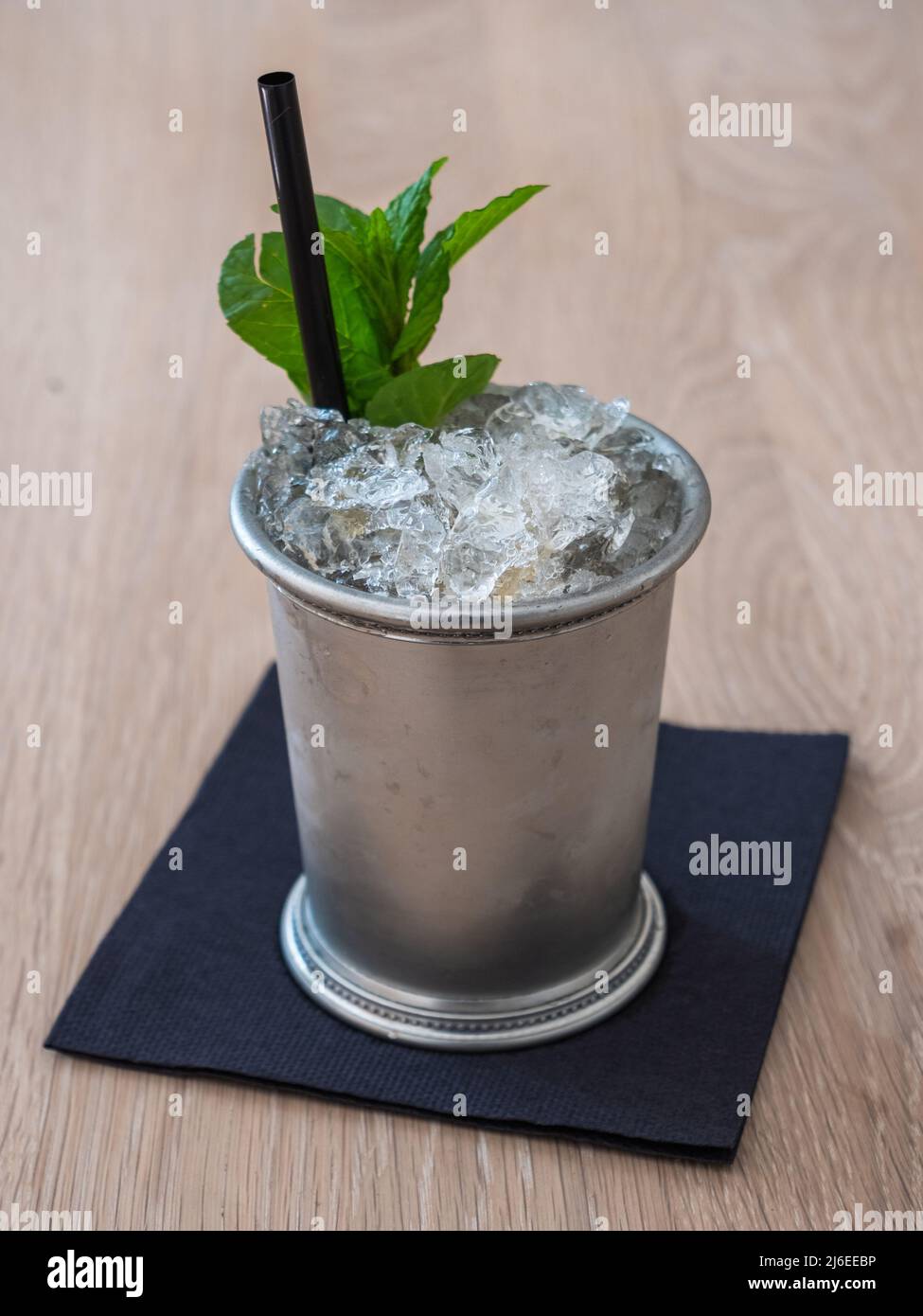 Cocktail Mint Julep con ghiaccio schiacciato in una Pewter Cup, con un rametto di menta e paglia Foto Stock