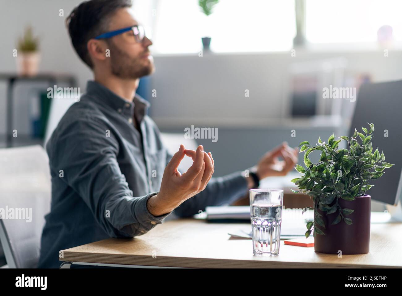 Calmo lavoratore in ufficio maschile maturo seduto alla scrivania con computer portatile, meditando, rilassante durante la giornata di lavoro stressante Foto Stock
