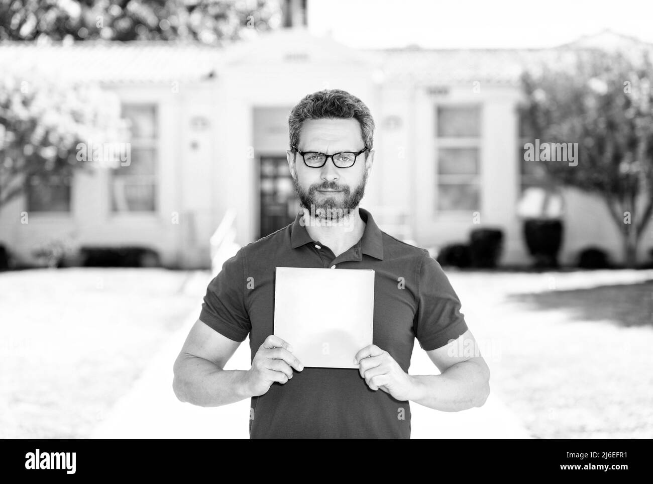 insegnante uomo in bicchieri mostrando foglio di carta, di nuovo a scuola Foto Stock