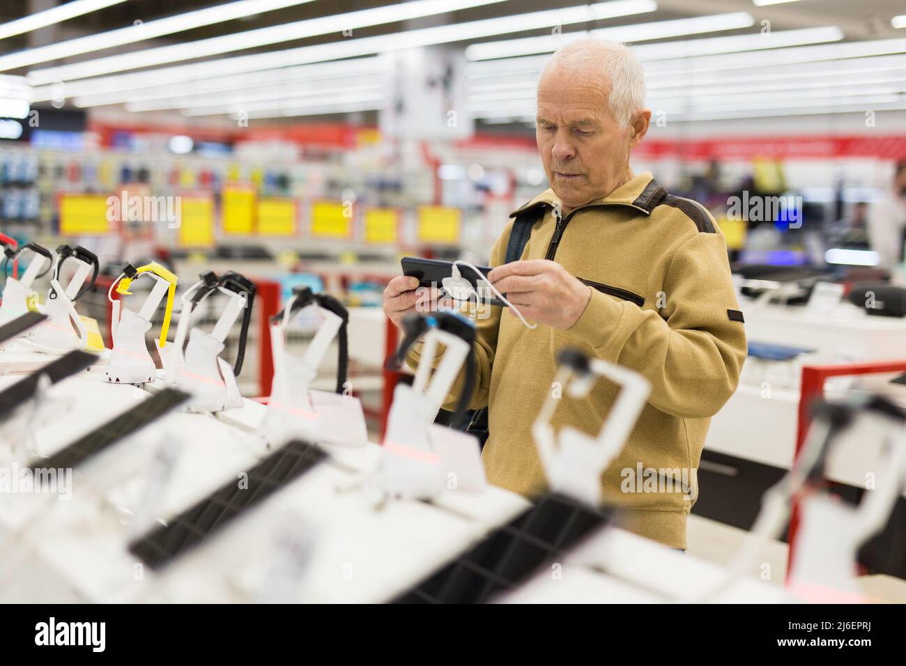 l'uomo anziano esamina il computer tablet nello showroom del negozio di elettronica Foto Stock