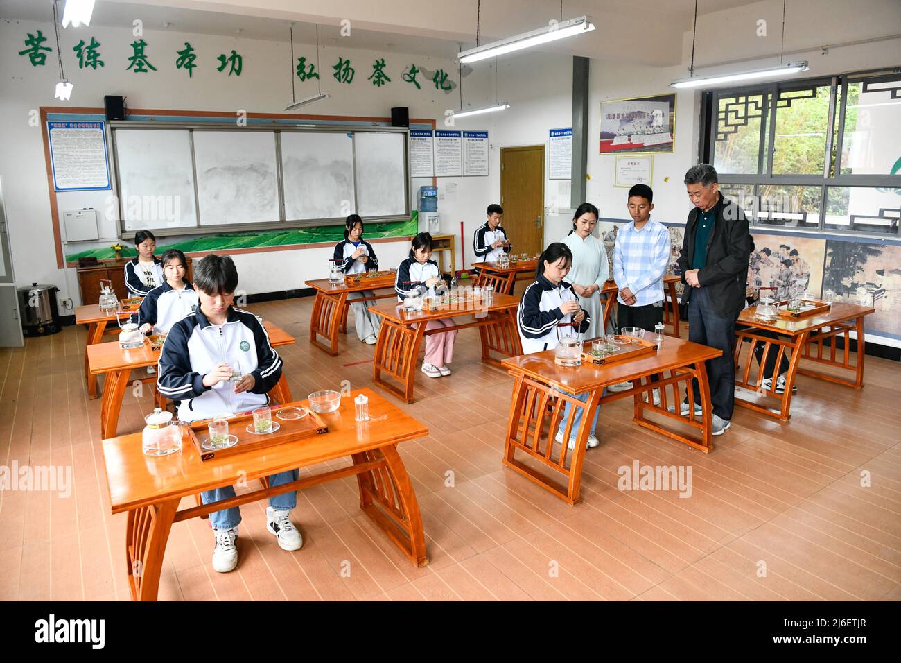 (220501) -- MEITAN, 1 maggio 2022 (Xinhua) -- Guo Jun (2nd R) e il suo insegnante Liu Xiaohua (1st R) guardano uno studente che prepara il tè ad una scuola tecnica locale nella contea di Meitan, nella provincia di Guizhou della Cina sudoccidentale, 29 aprile 2022. Impegnato a tostare le foglie di tè su un piano cottura, Guo Jun si crogiola nell'aroma fresco riempiendo un laboratorio nella contea di Meitan. Dopo essersi laureato all'Università di Guizhou nel 2016, Guo tornò nella sua città natale per lavorare in una compagnia di tè, dove imparò a preparare il tè da un maestro locale. Nel 2018 divenne istruttore presso una scuola tecnica locale due anni dopo. Affinare le proprie abilità di tè-fare richiesta Foto Stock