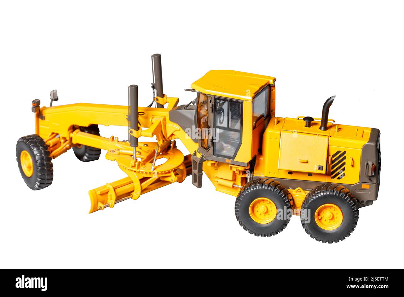 Modello giocattolo di trattore stradale giallo da costruzione con lama regolabile su sfondo bianco, messa a fuoco selettiva. Foto Stock