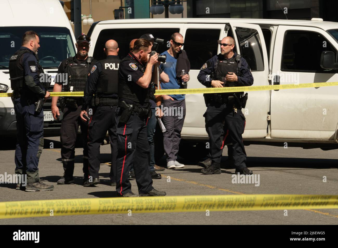 Ottawa, Ontario, Canada - 30 aprile 2022: Un ufficiale dei servizi di polizia di Ottawa (OPS) fotografa la scena di un incidente dietro nastro giallo della polizia. Foto Stock