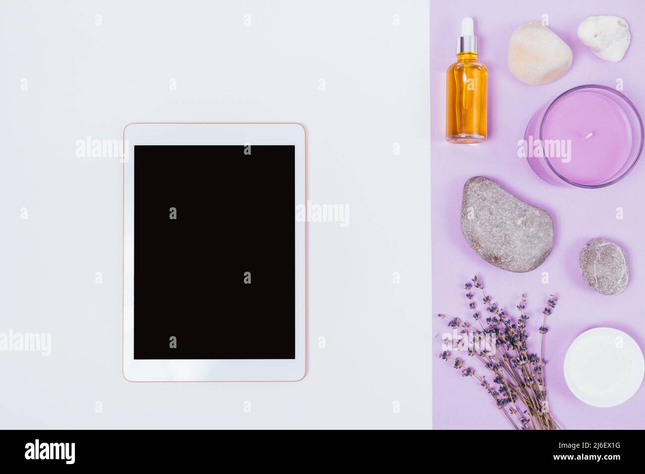 Composizione Spa con tablet pc accanto all'olio cosmetico, candela e fiori di lavanda su sfondo bianco, posa piatta. Foto Stock