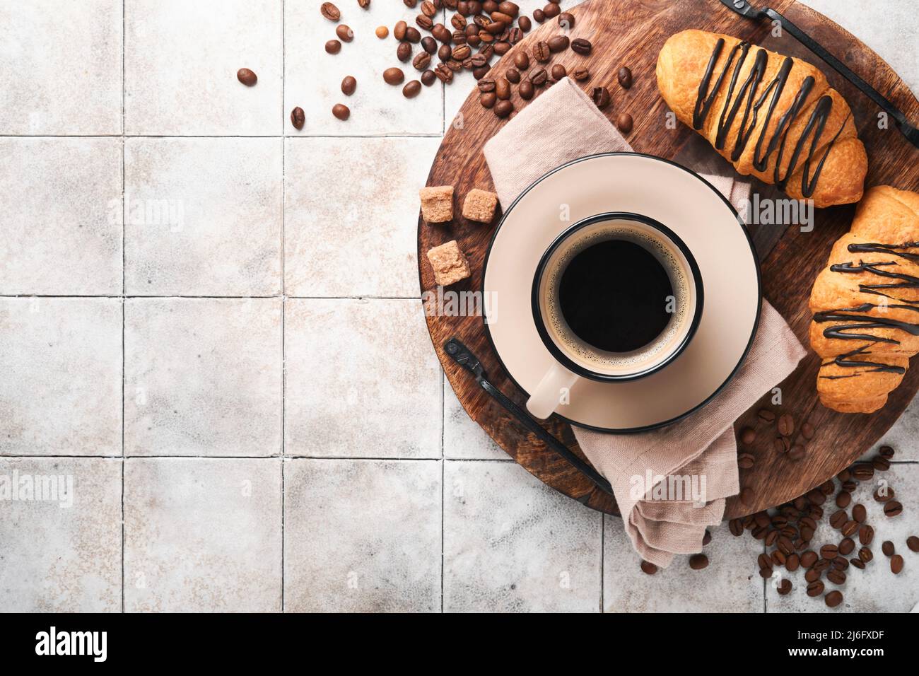 Caffè e croissant. Caffè espresso e croissant con cioccolato su un vecchio tavolo di piastrelle cracked. Colazione croissant perfetta al mattino. Stile rustico Foto Stock