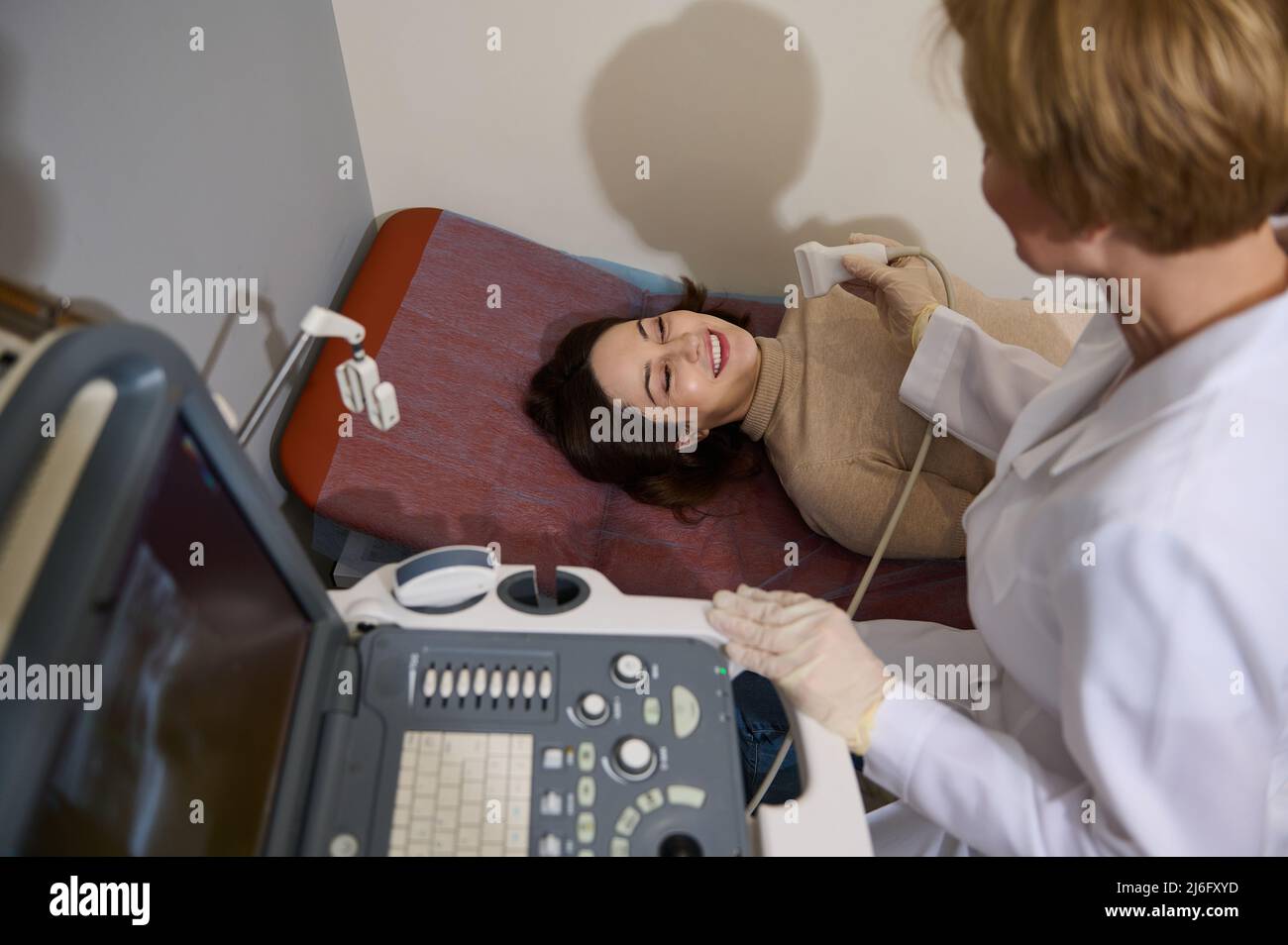 Medico radiologo che dà bella giovane paziente una diagnostica a ultrasuoni per la prevenzione tempestiva delle malattie, ultrasuoni Foto Stock