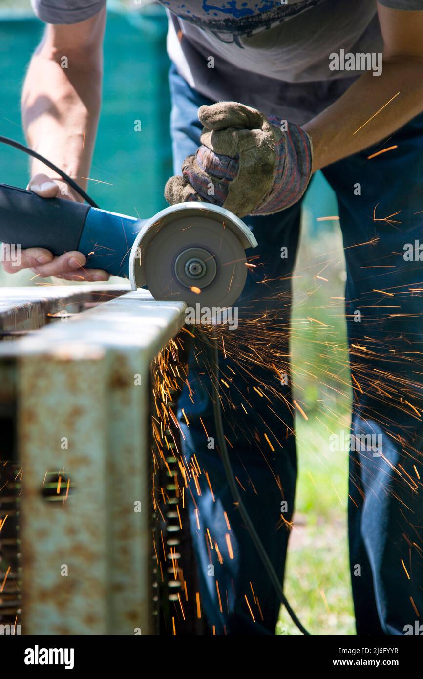 Un uomo taglia una struttura metallica con un attrezzo speciale Foto Stock