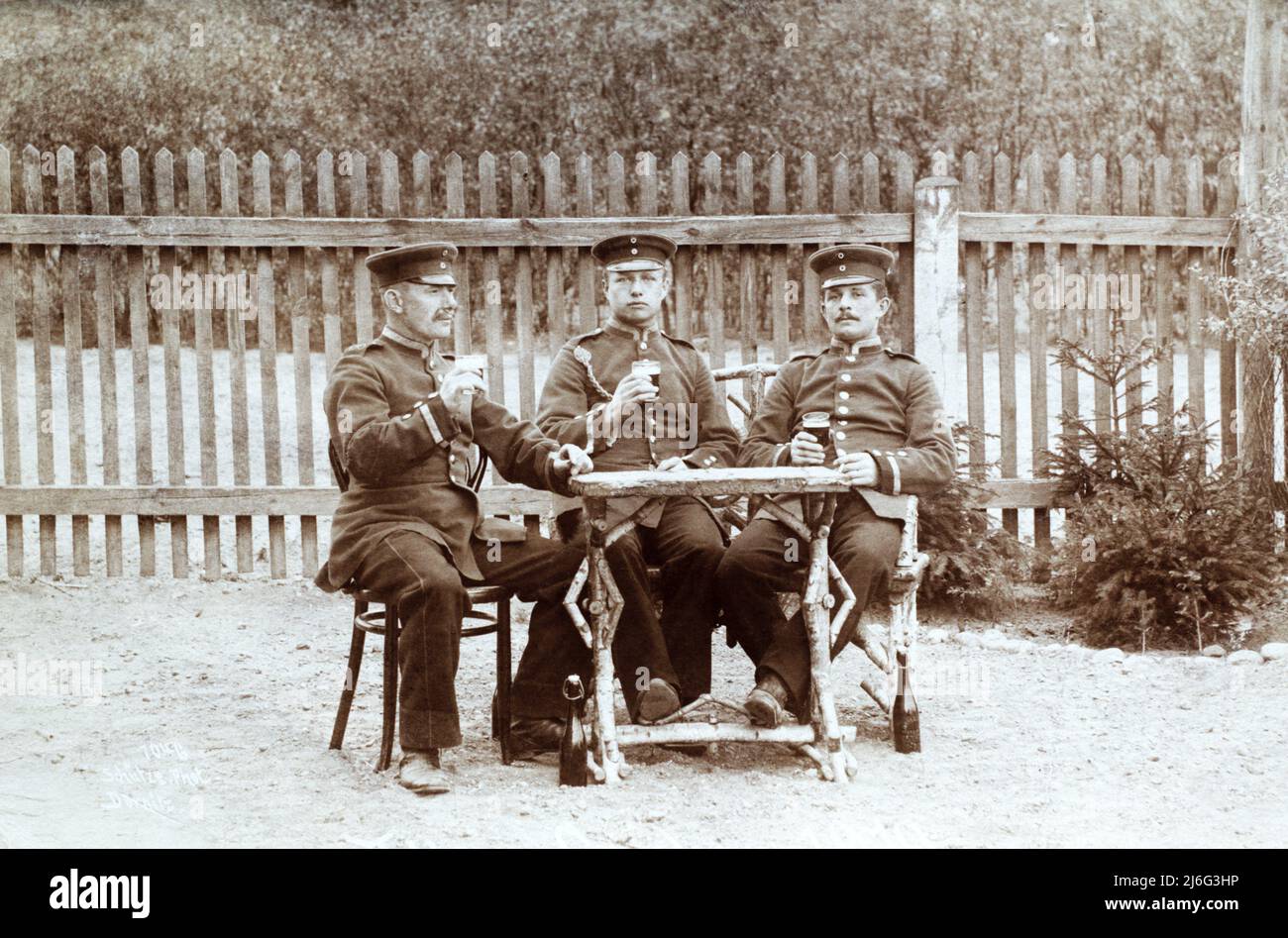 Tre soldati dell'esercito tedesco, gli Unteroffiziers, si sono seduti intorno ad un tavolo bevendo birra. Il soldato medio ha un cordone di marchmanship. Si ritiene provenga da Merseburg c.. 1910. Foto Stock