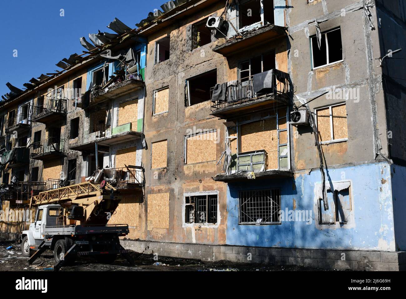 Un camion gru vicino al danneggiato edificio di appartamenti da shelling russo a Dobropillya. La Russia è stata costretta a spostare forze 'disparate e disparate' nell'Ucraina orientale, secondo l'ultimo rapporto di intelligence del Ministero della Difesa del Regno Unito di sabato. Il Regno Unito ha affermato che "probabilmente queste unità soffrono di un morale indebolito". (Foto di Andriy Andriyenko / SOPA Images/Sipa USA) Foto Stock