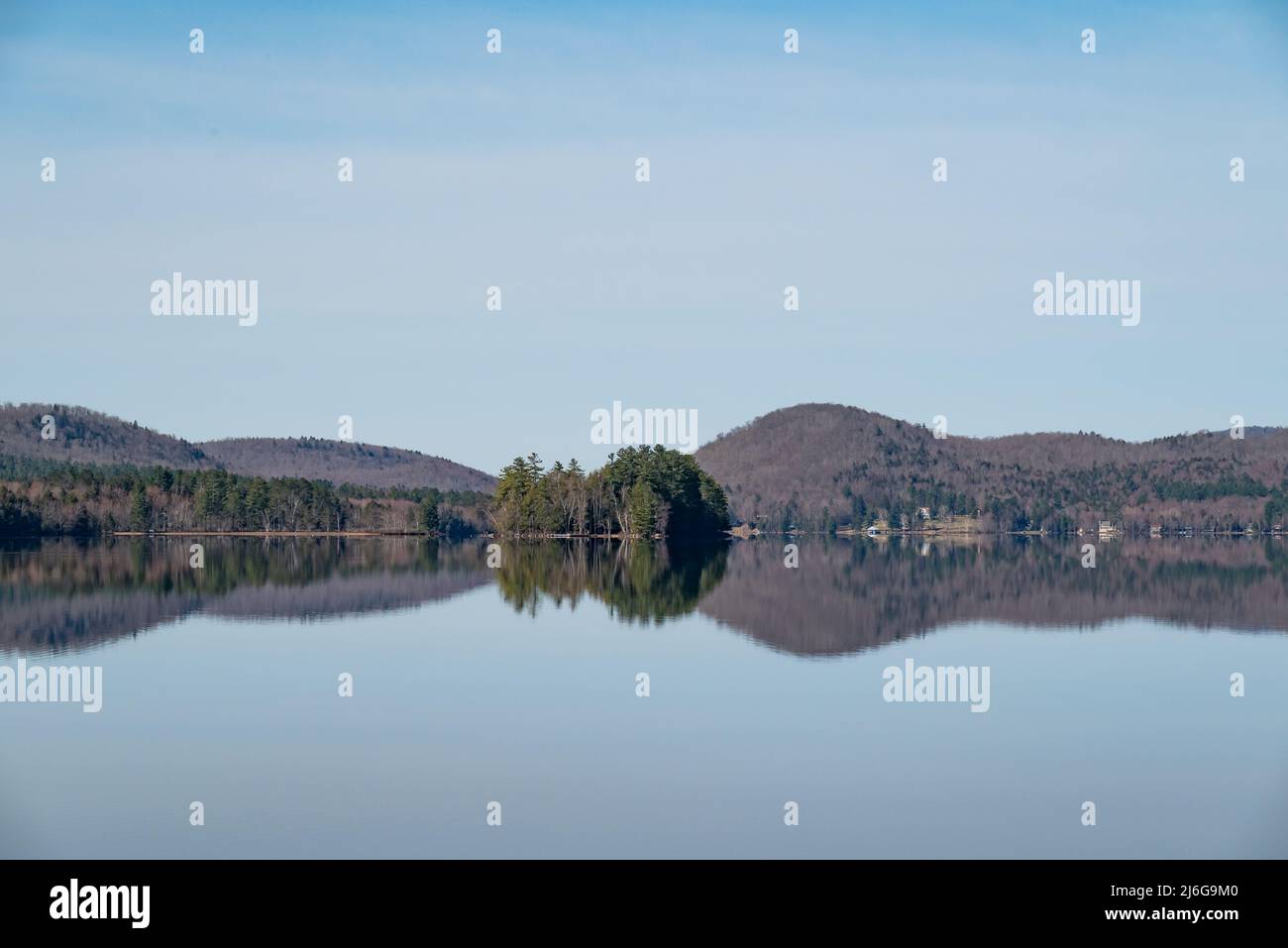 Una vista del lago piacevole nelle montagne di Adirondack in una giornata tranquilla e limpida con l'isola di Tapawingo e la costa distante riflessa nell'acqua Foto Stock