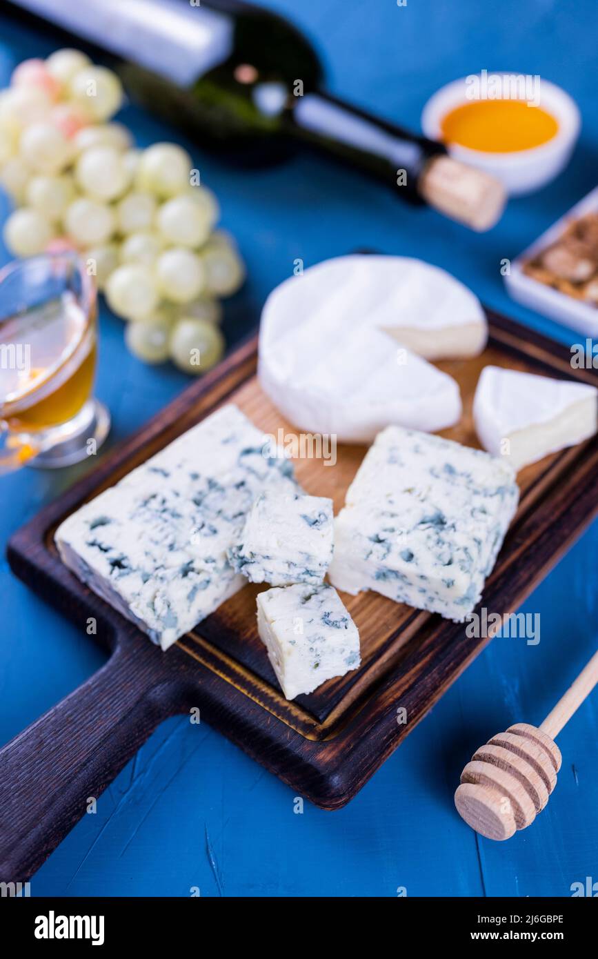 antipasto formaggio dor blu e camembert su un bordo di legno con miele e uva Foto Stock