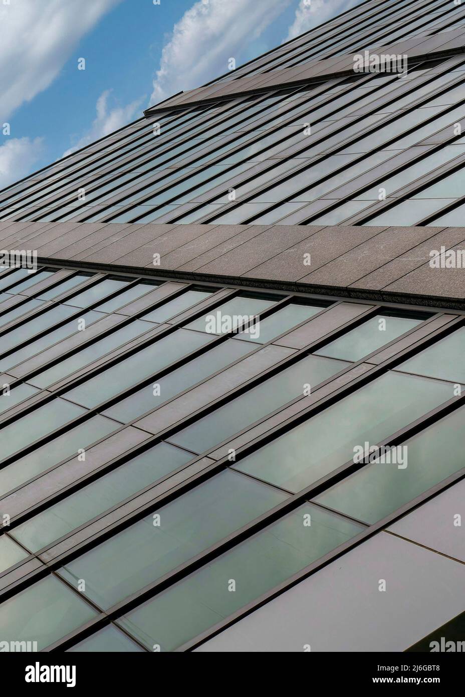 Verticale Bianco nuvole soffy basso angolo di vista di un edificio facciata con vetro riflettente w Foto Stock