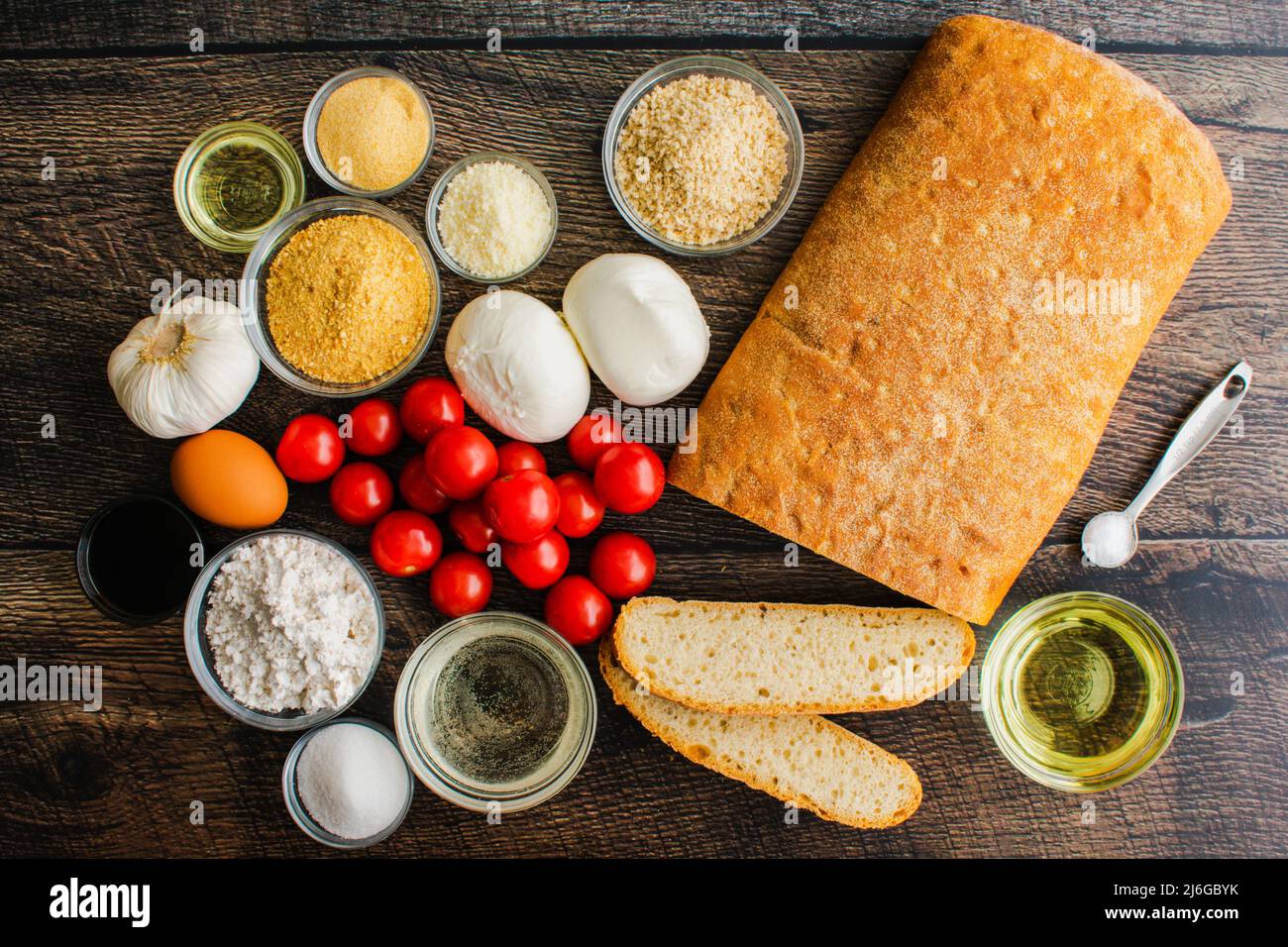 Vista dall'alto della burrata fritta con gli ingredienti della salsa di pomodoro ciliegino: Ingredienti per una mozzarella fritta, pomodoro e antipasto ciabatta Foto Stock