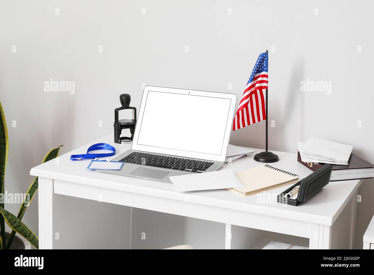 Posto di lavoro con un moderno computer portatile, lettere e bandiera USA vicino alla parete della luce Foto Stock