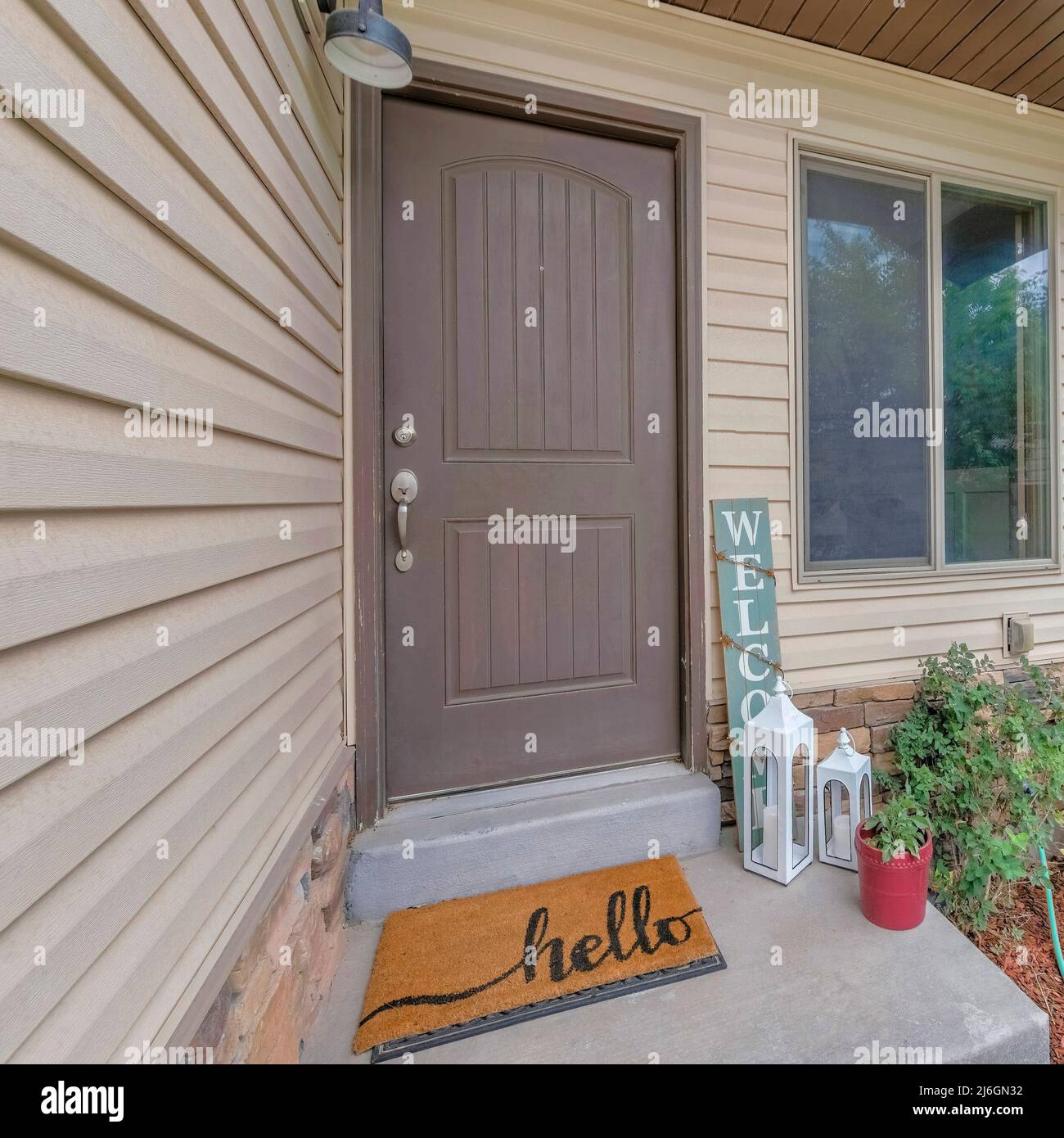 Facciata quadrata della casa con lap siding beige in vinile e porta anteriore grigia vicino alla finestra Foto Stock
