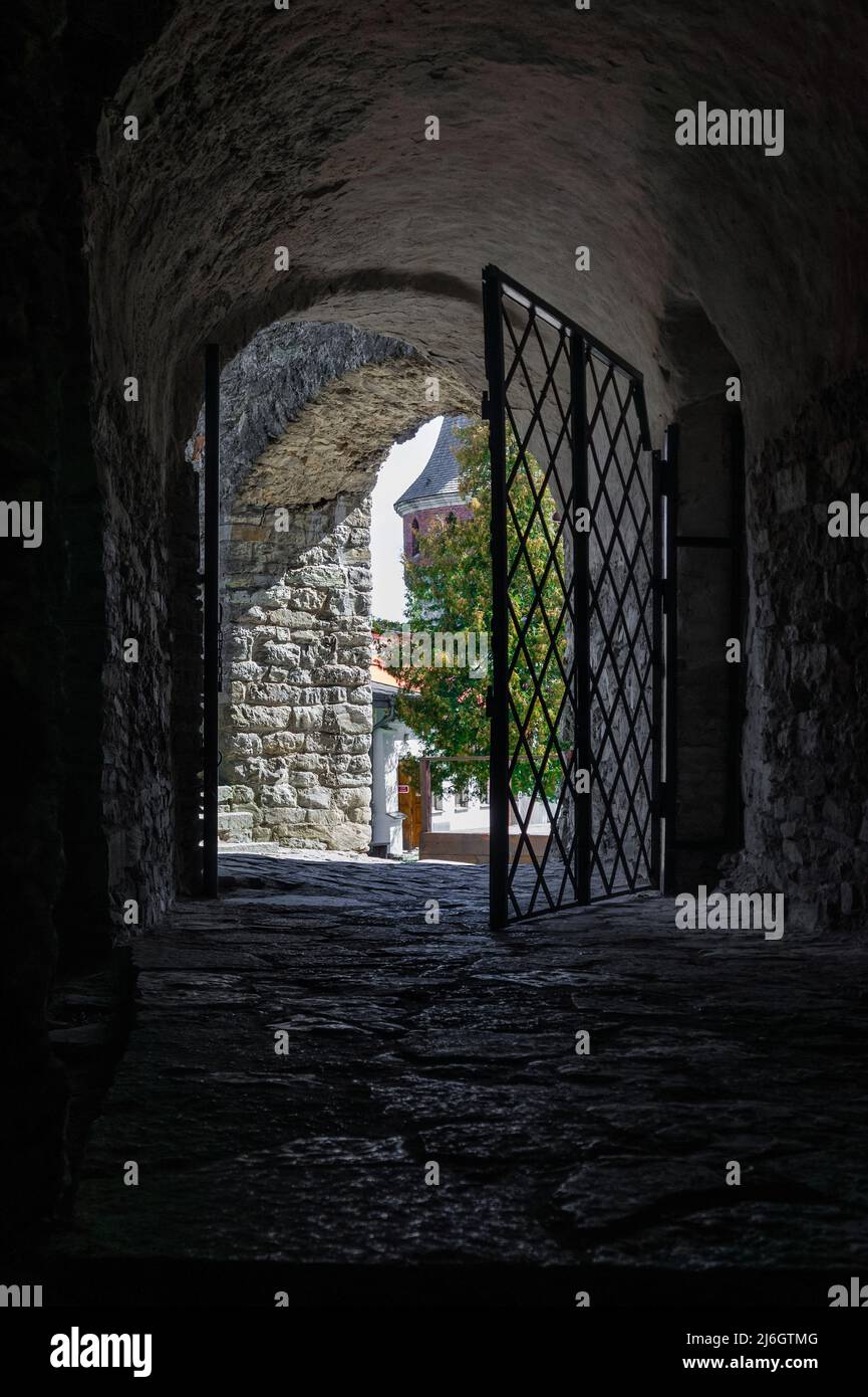 Passaggio medievale ad arco del castello. Passaggio ad arco da nero freddo umido a luce intensa con cella in grata di ferro arrugginita. Foto Stock