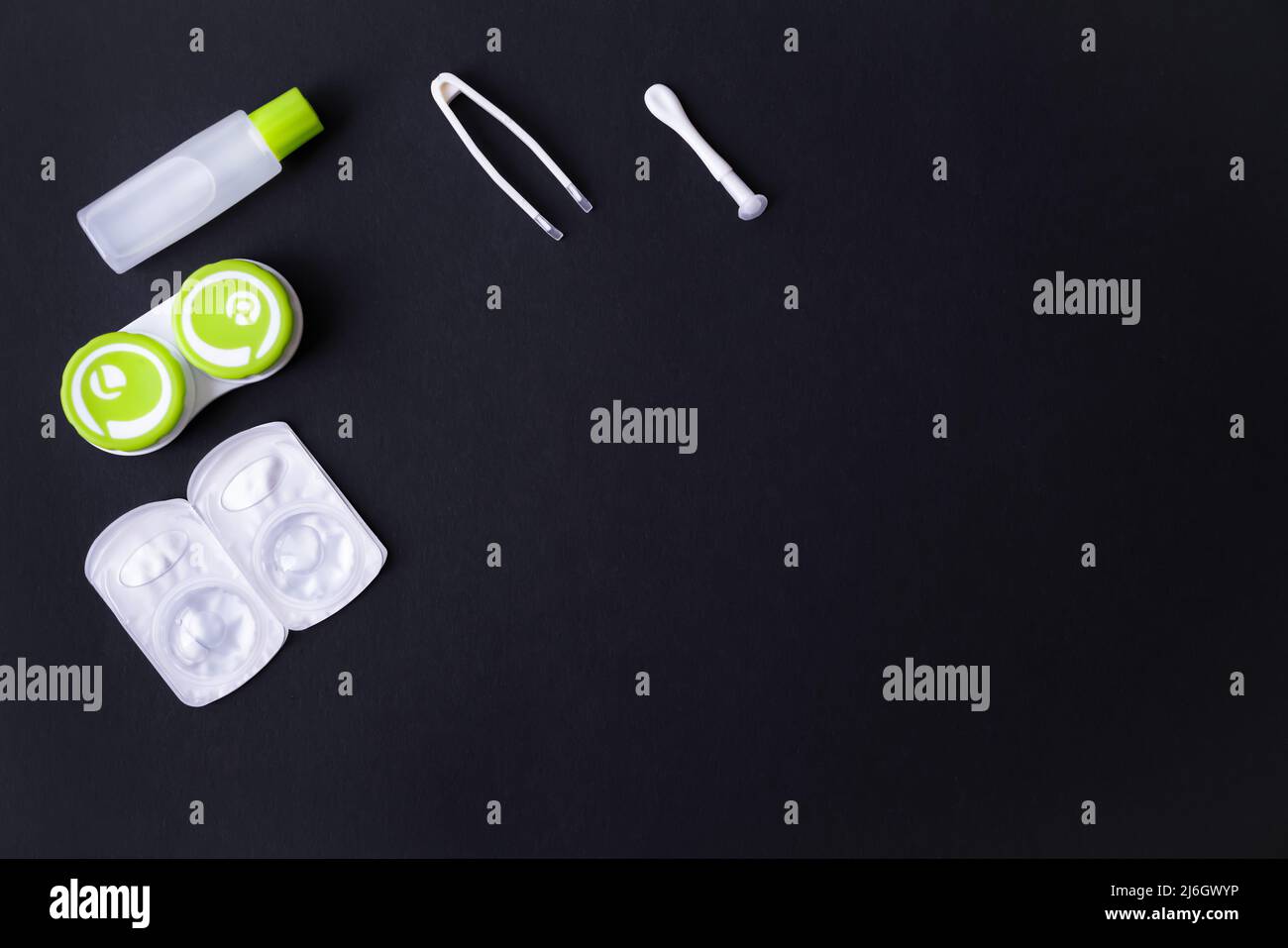 Set di lenti a contatto con contenitore, pinzette, ventosa e bottiglia con soluzione su sfondo nero, vista dall'alto, spazio di copia Foto Stock