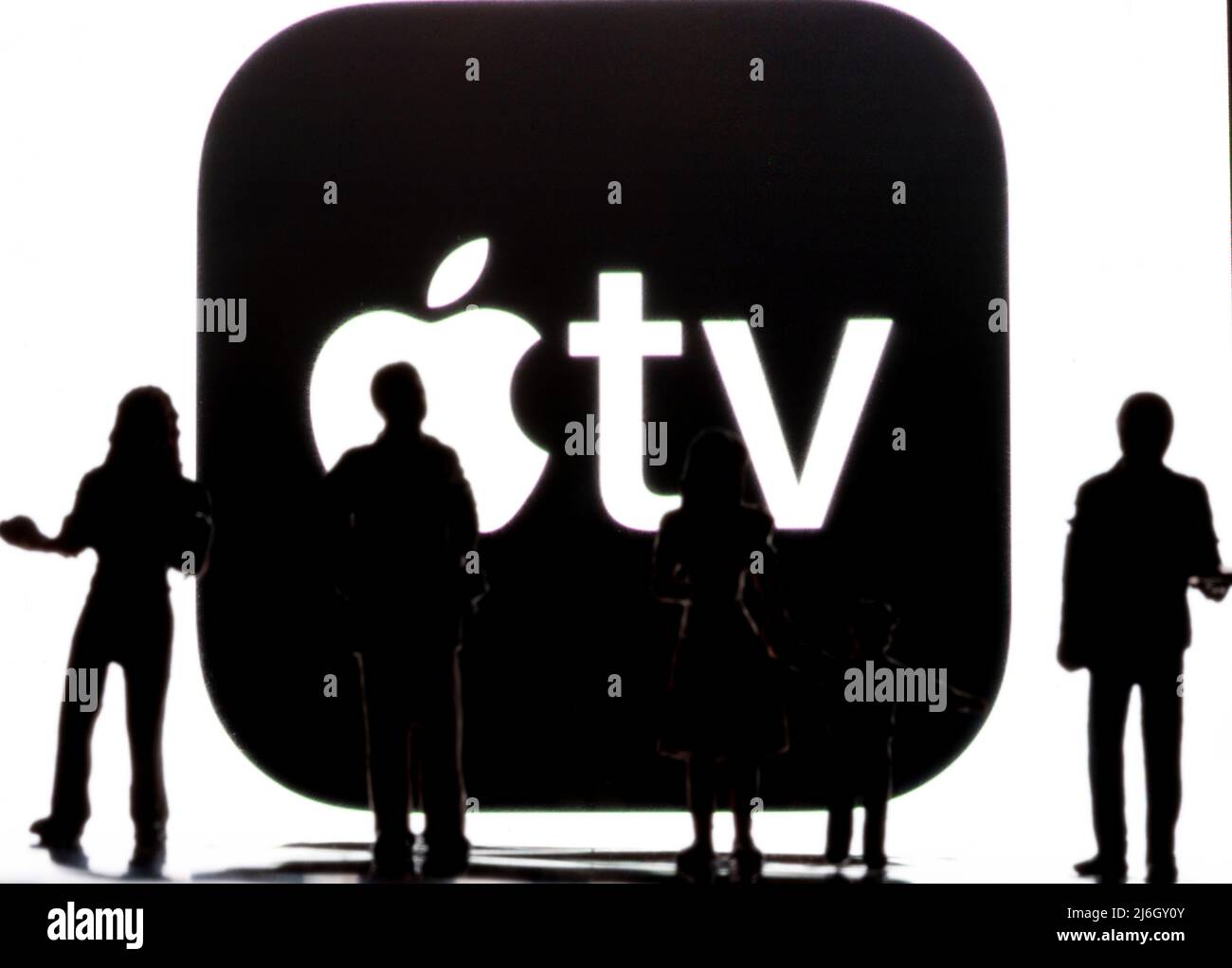 Figure in miniatura che si trovano davanti a un logo Apple TV sfocato sullo smartphone Foto Stock