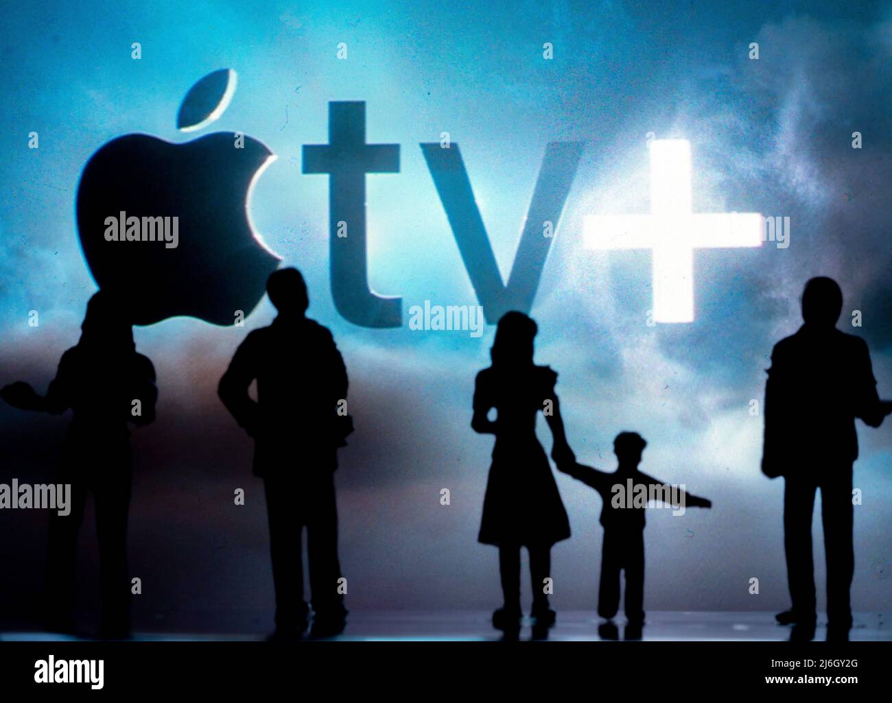 Figure in miniatura che si trovano di fronte al logo sfocato di Apple TV+ sullo smartphone Foto Stock