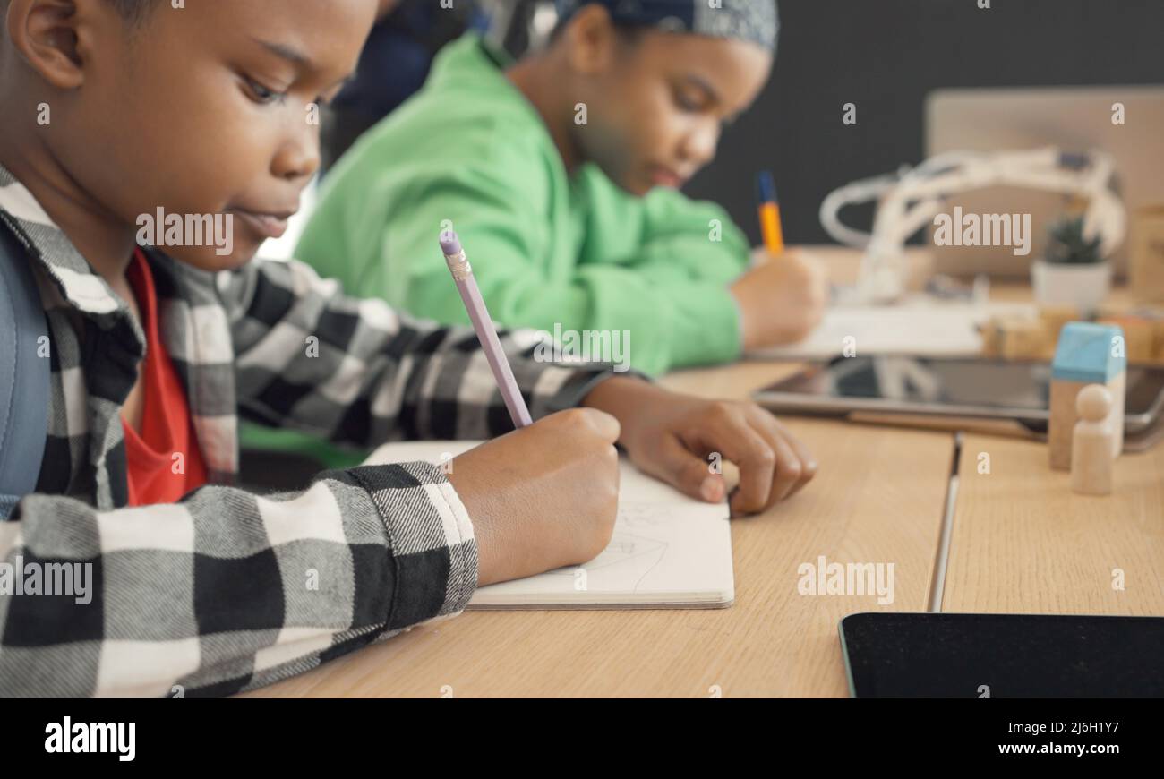 Studente in scuola materna internazionale che scrive un libro insieme nella classe della scuola elementare, gli alunni che si divertono a studiare in classe. Foto Stock