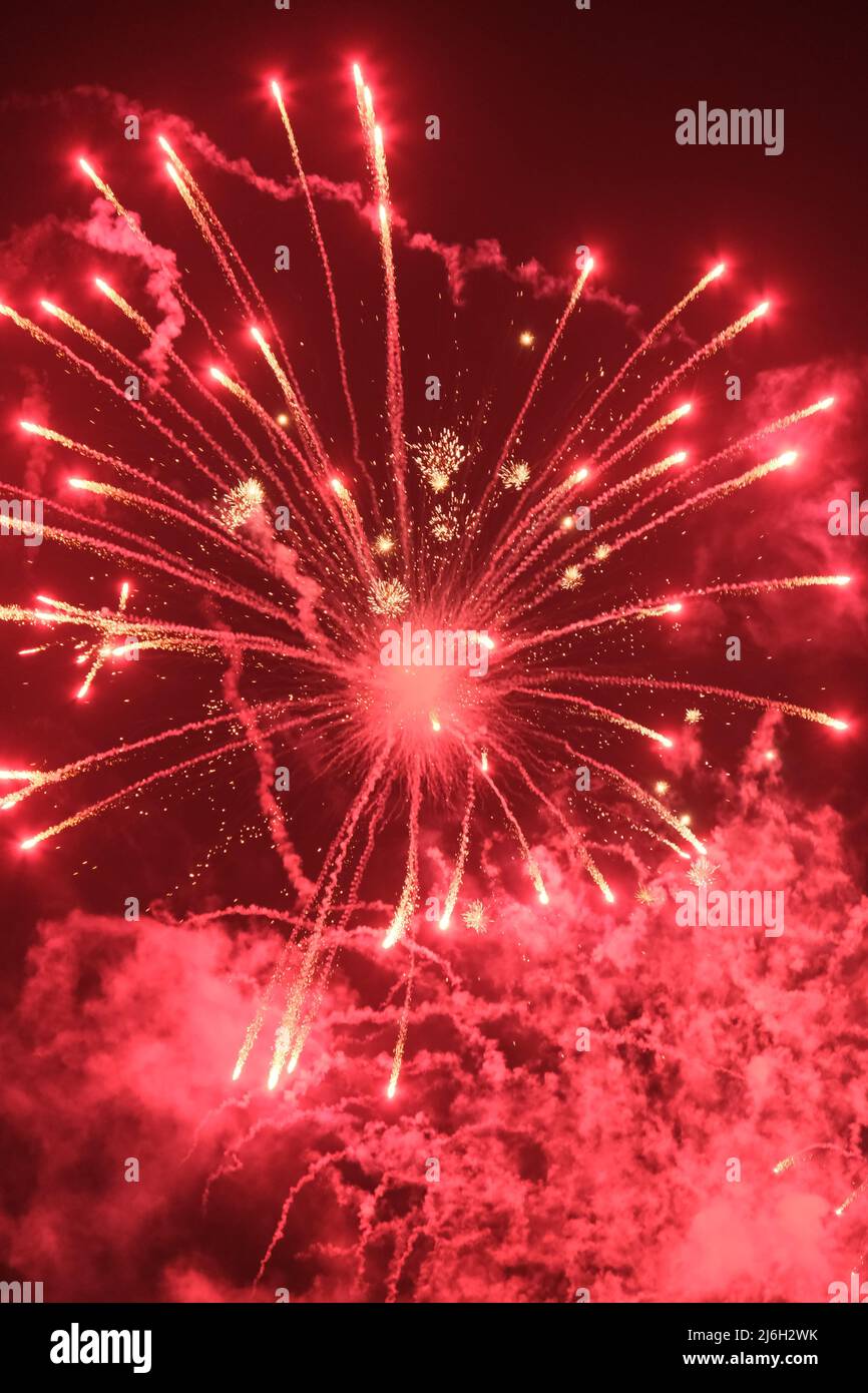 Un'esplosione di fuochi d'artificio e percorsi di fumo in un cielo notturno Foto Stock