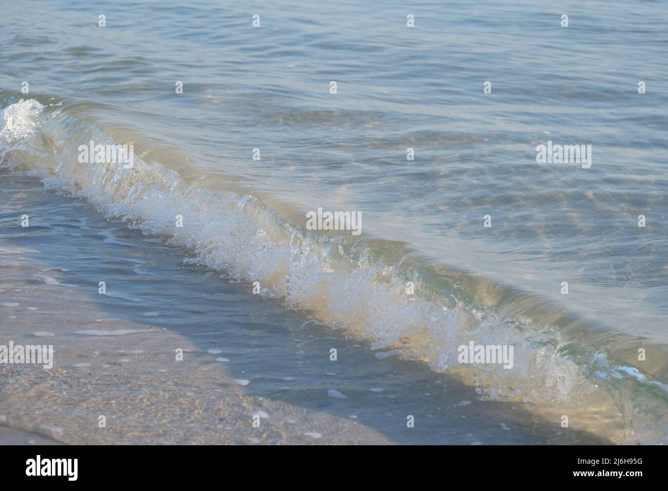 Onda di marea cristallina su una spiaggia di sabbia Foto Stock