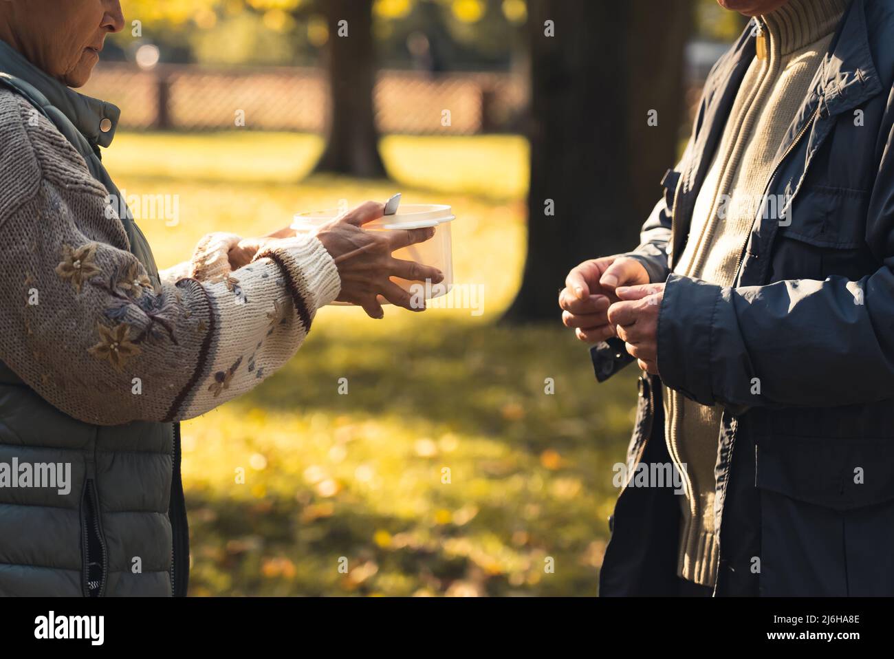 Mani di due senzatetto caucasici che passano sopra una pentola di minestra fatta in casa da volontari dell'organizzazione di carità. Concetto di supporto. Foto di alta qualità Foto Stock