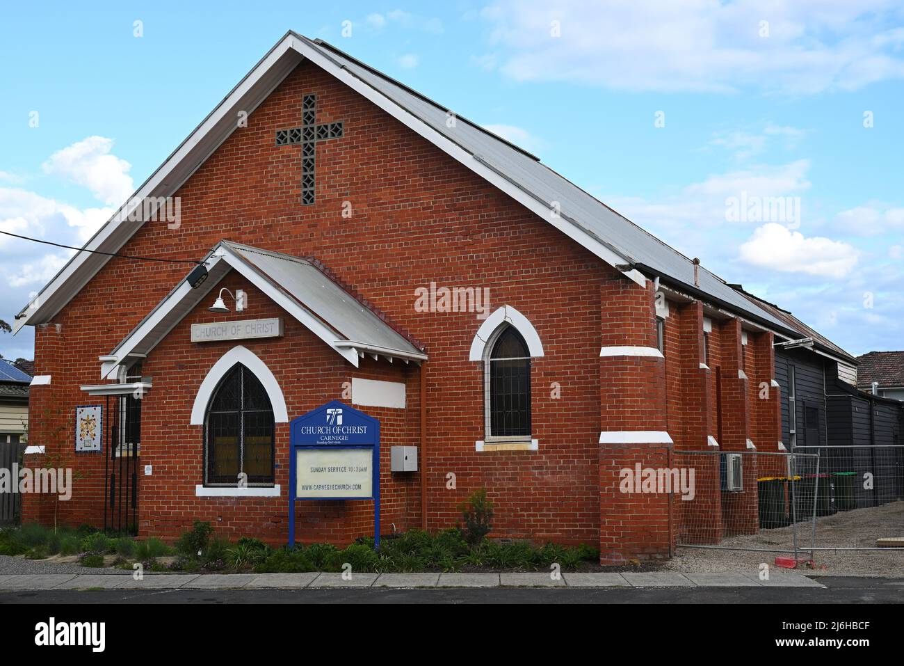 Esterno della chiesa di Cristo in mattoni rossi, Carnegie, con accesso alla sua estensione posteriore in legno bloccato da una recinzione temporanea Foto Stock