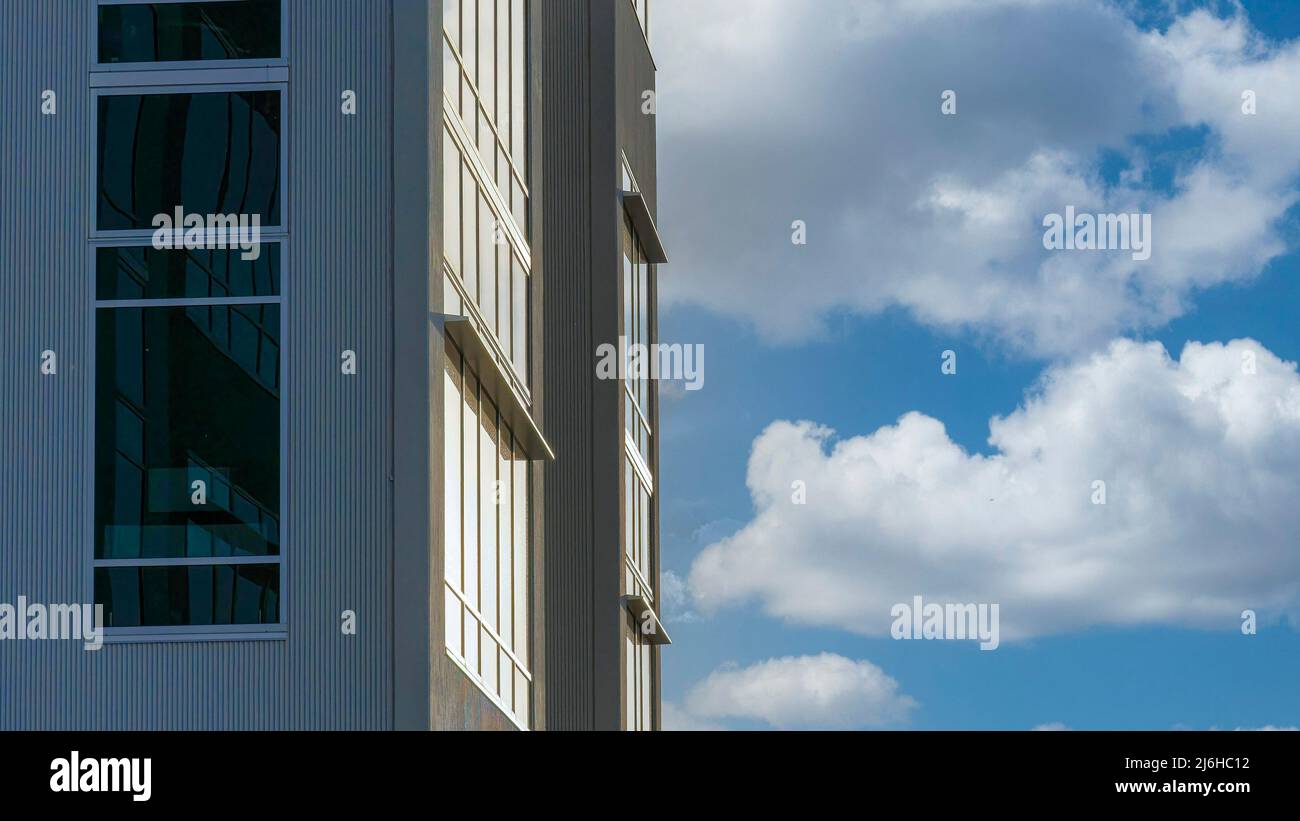 Panorama Nubi bianche soffy Tramonto che si riflette sulle pareti di vetro dell'edificio Foto Stock