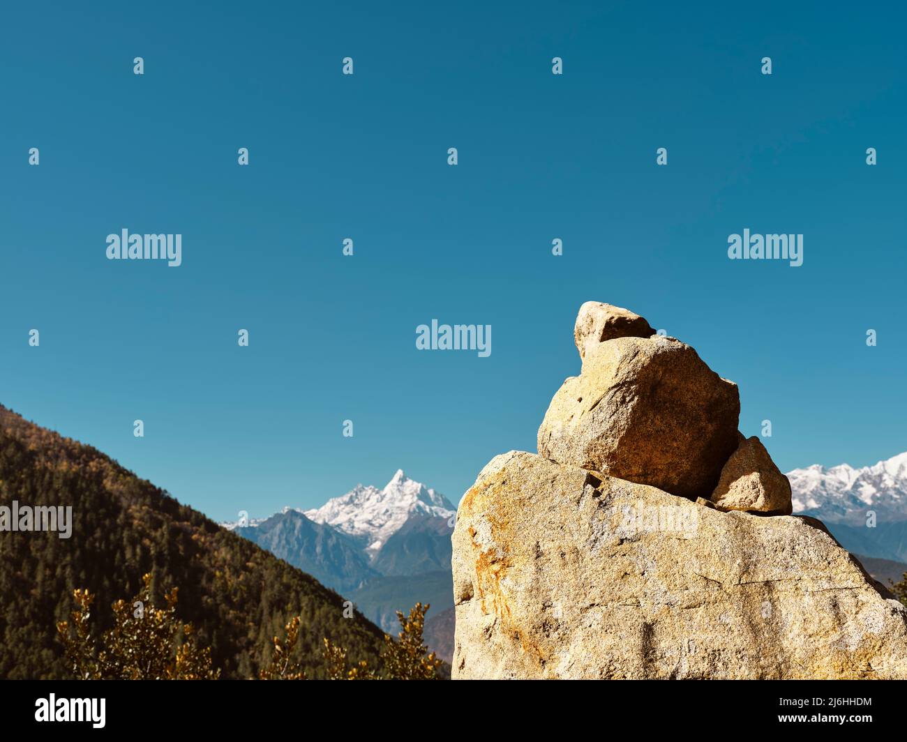 enormi pietre di preghiera sotto il cielo blu con la catena montuosa di meili innevate sullo sfondo, sichuan, cina Foto Stock