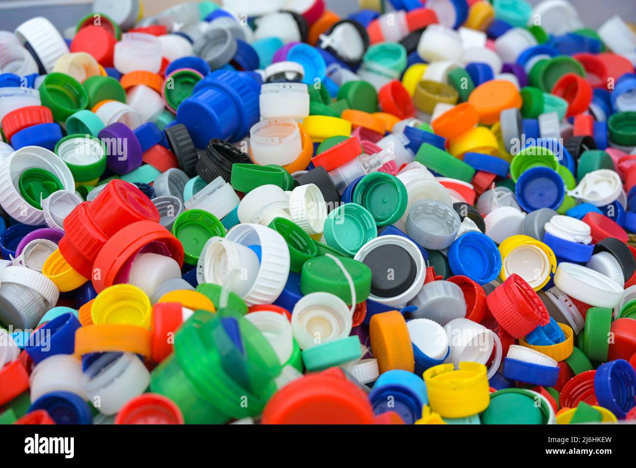 Molti coperchi colorati in plastica delle bottiglie, rifiuti scartati raccolti per il riciclaggio, protezione ambientale e concetto di stile di vita sostenibile, pieni Foto Stock