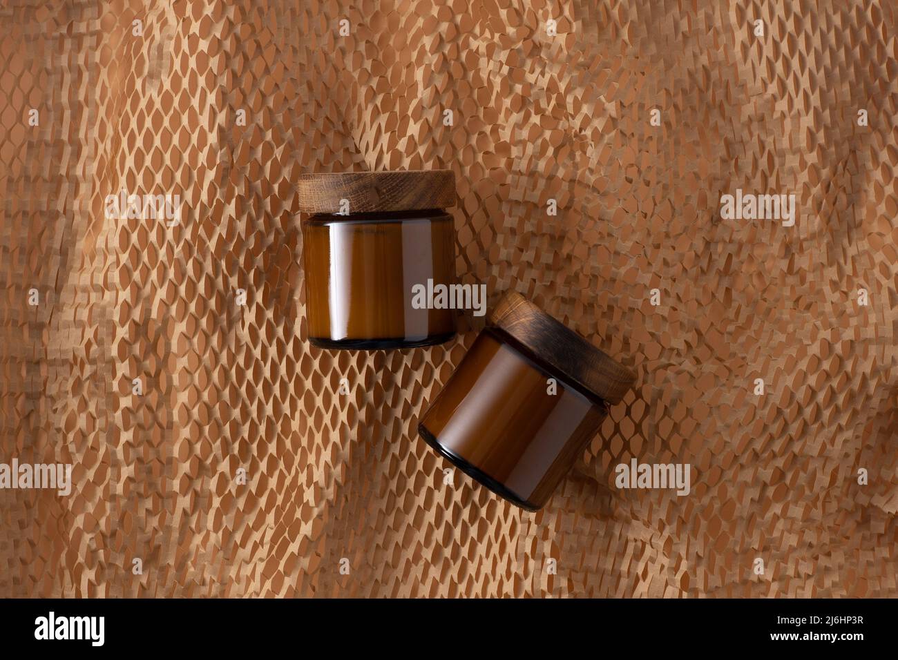 Contenitore per cosmetici e creme. Vaso marrone in vetro con coperchio in legno. Sfondo beige. Concetto monocromatico. Posizionare un'etichetta. Vasetti di crema. Bellezza e cura. Minimalismo Foto Stock