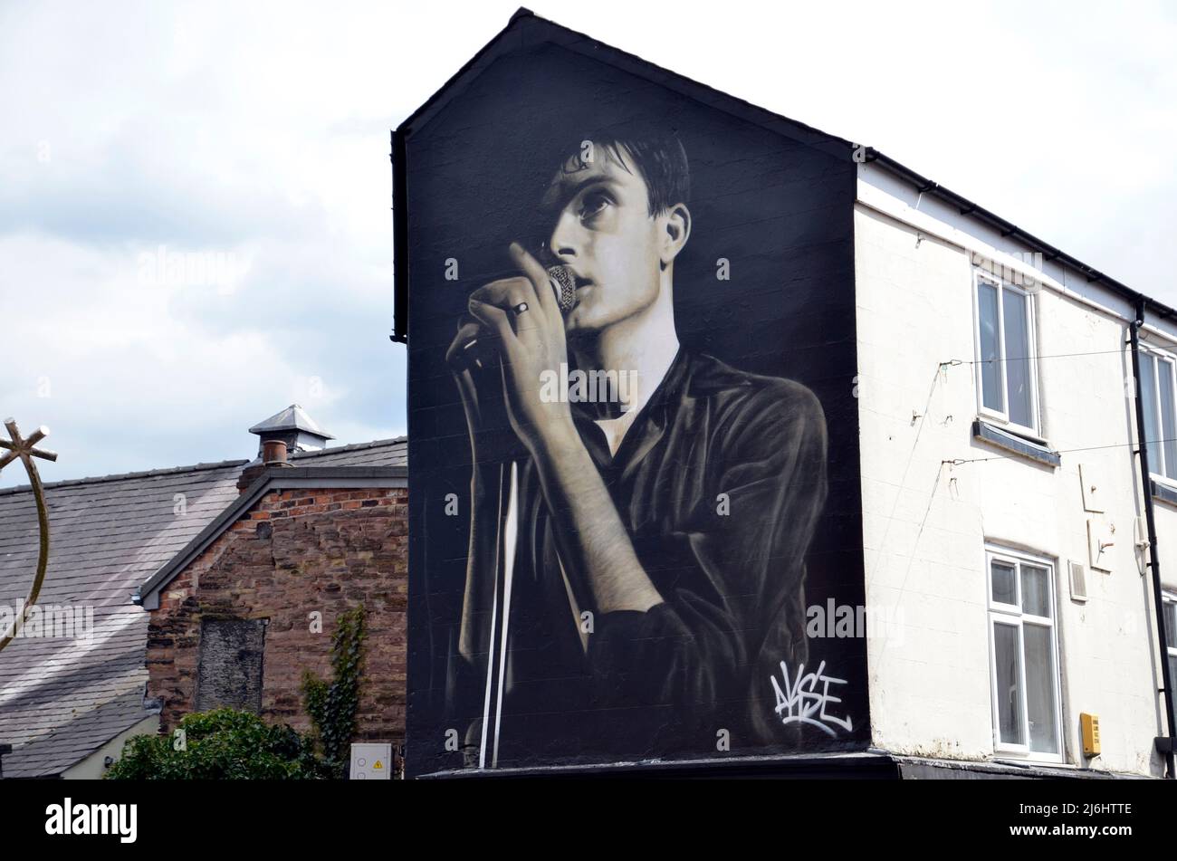 Un murale a Macclesfield dell'artista di strada Akse in omaggio a Ian Curtis, cantante principale della divisione di gioia, che è stato sopportato nella città di Cheshire. Foto Stock
