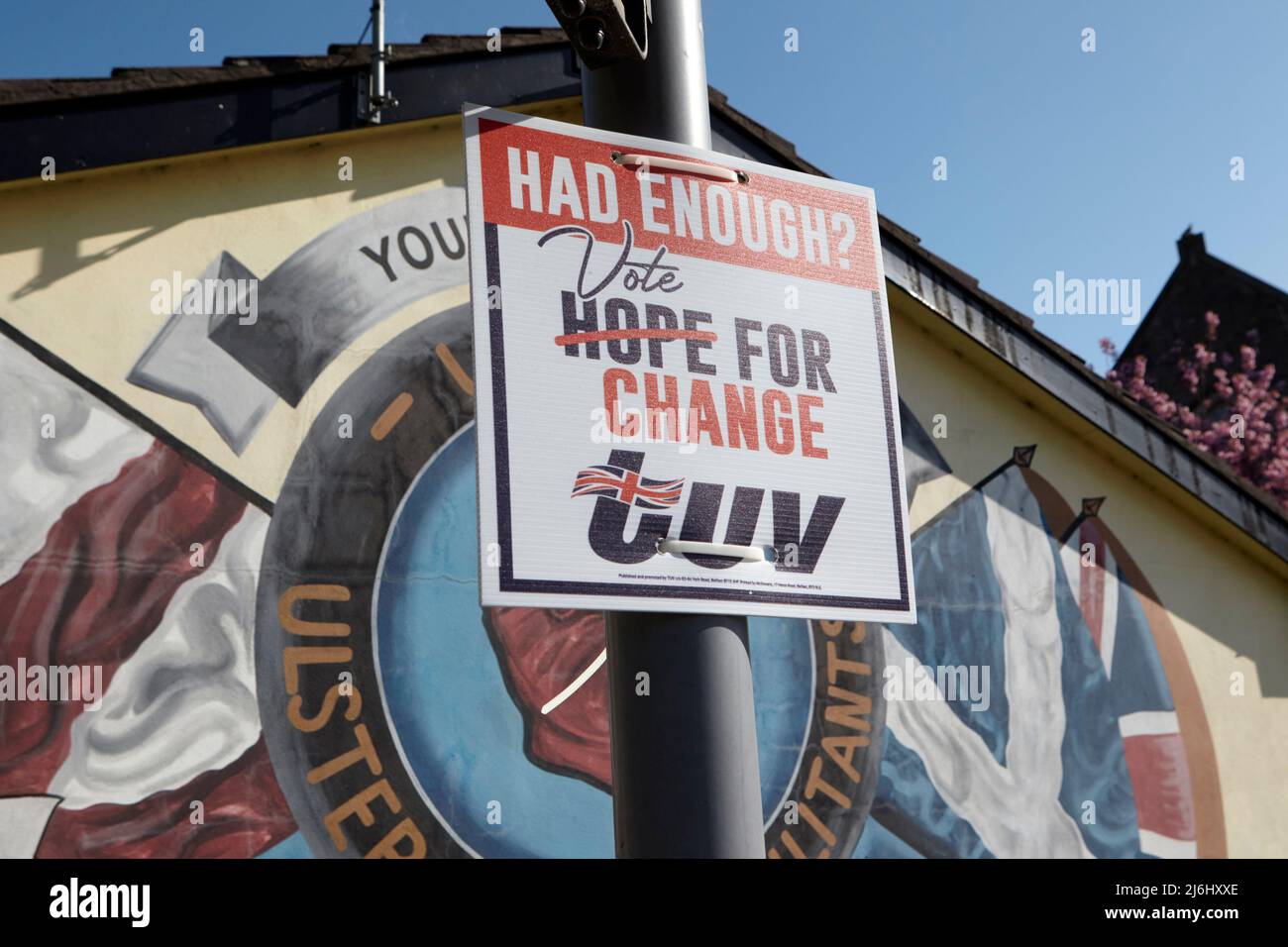 TUV (Traditional Unionist Voice) poster elettorale accanto ai murales paramilitari Loyalist su 'Freedom Corner' Lower Newtownards Road, East Belfas Foto Stock