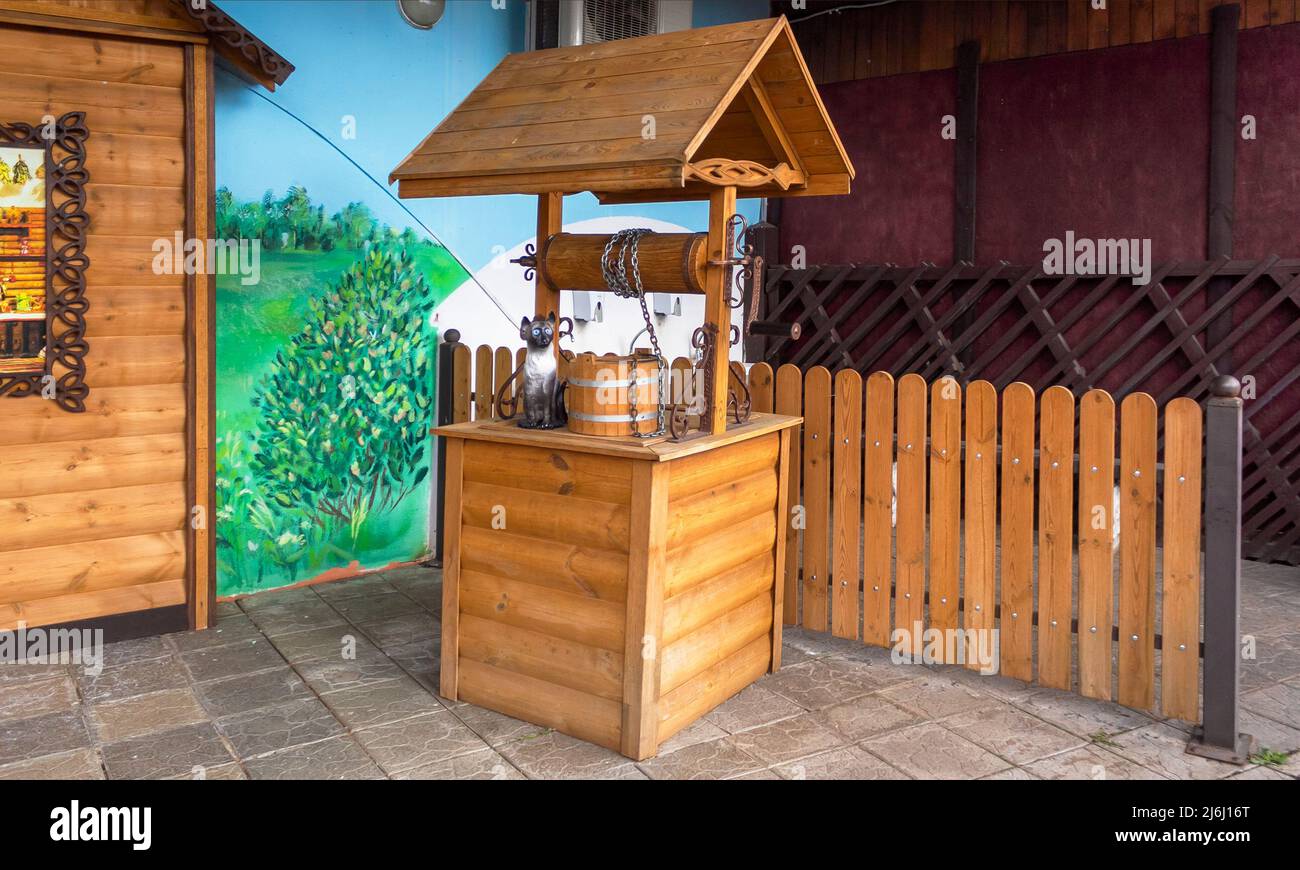 Pozzo di legno - installazione sullo sfondo del verde. Pozzo di legno nel parco. Foto Stock