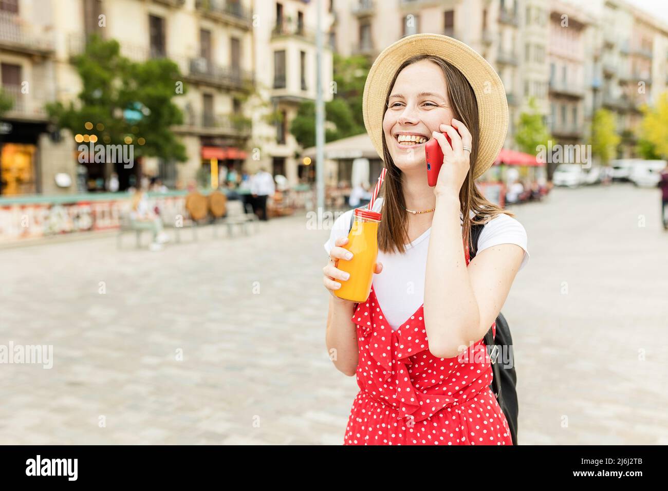 Giovane donna che parla al telefono cellulare mentre cammina all'aperto per strada. Foto Stock