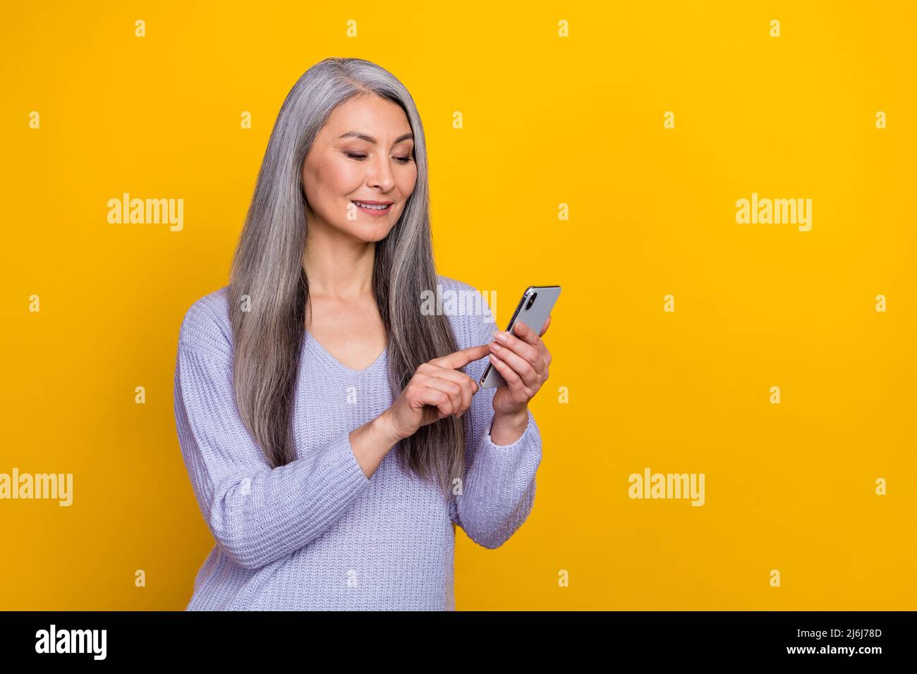 Foto di affascinante signora pensionato sbloccare il suo smartphone leggere ebook rispondere telefono cellulare chiamata isolato su sfondo giallo Foto Stock