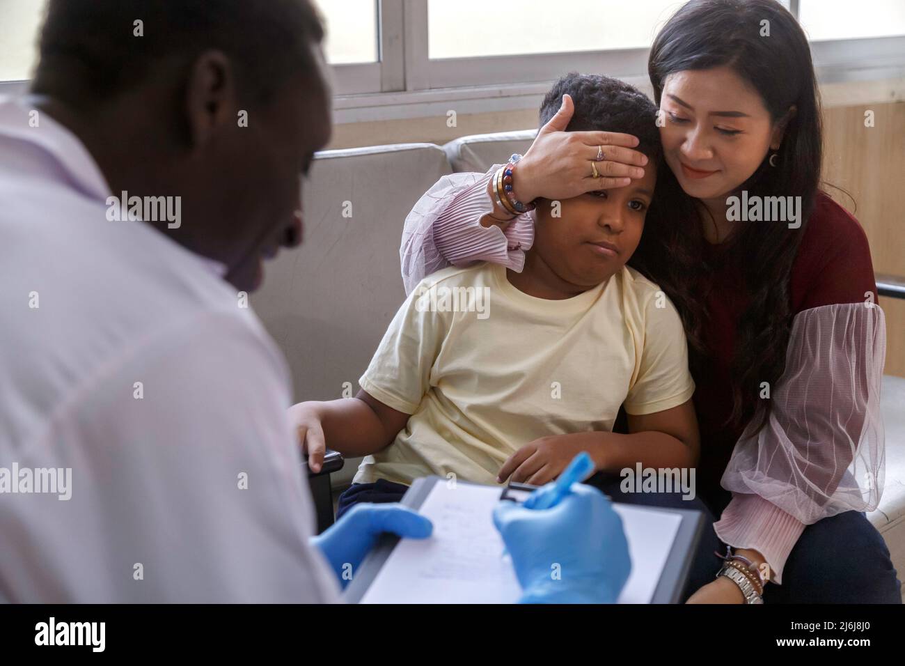 psicologa di famiglia. madre asiatica e suo ragazzo parlano con il medico psicoterapista afro-americano durante la sessione di terapia in ospedale. Foto Stock