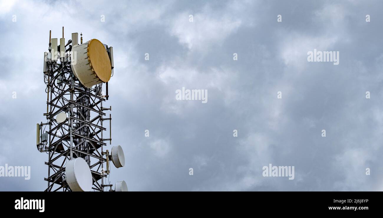 Antenne a microonde a basso tamburo su torre alta. 5G comunicazione cellulare per telefonia mobile e trasmissione dati video. Punto di telecomunicazione Foto Stock