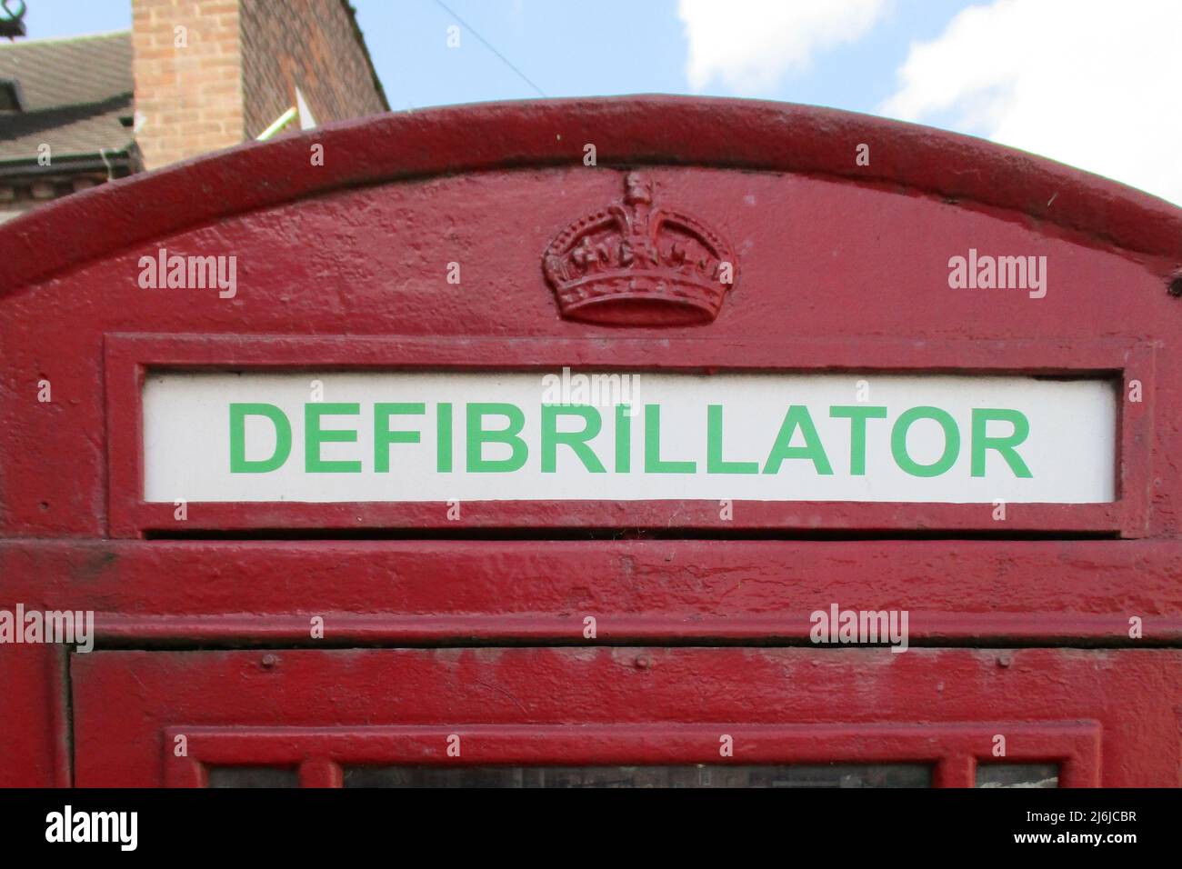 Primo piano di una vecchia scatola del telefono di colore rosso chiaro per l'uso del defibrillatore, in caso di emergenza, in una città in Inghilterra Foto Stock