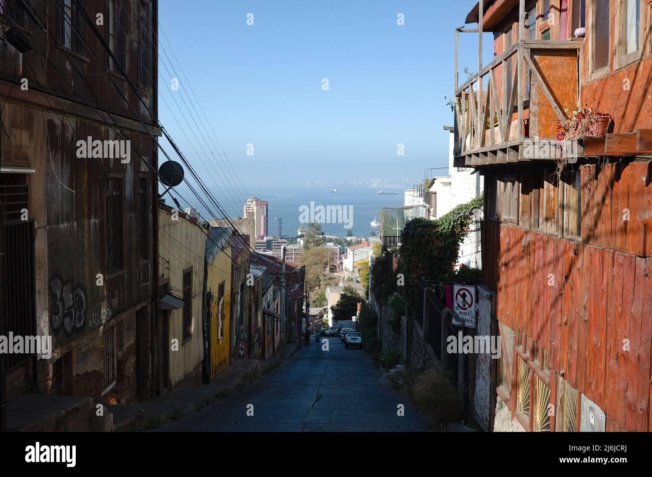 Valparaiso, Cile - Febbraio, 2020: Strada stretta nella parte vecchia della città che da collina giù per l'oceano. Vecchie case di legno sulla collina in zona non turistica Foto Stock
