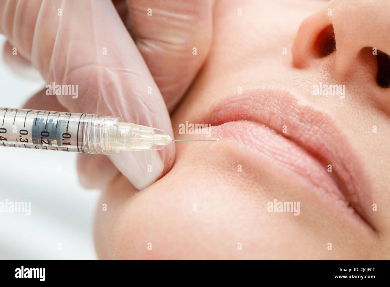 Primo piano delle mani del cosmetologo che fa l'iniezione botox nelle labbra femminili. Correzione della forma del labbro, aumento del labbro. Foto Stock