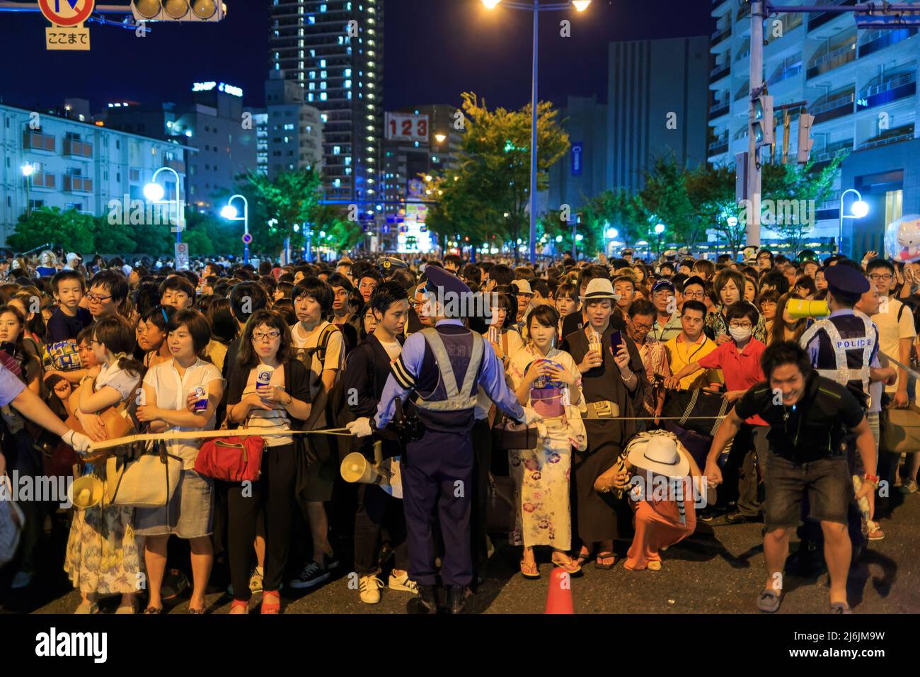 Osaka, Giappone - 25 luglio 2015: Gli ufficiali della polizia trattengono la folla di persone in strada dopo il festival estivo Foto Stock