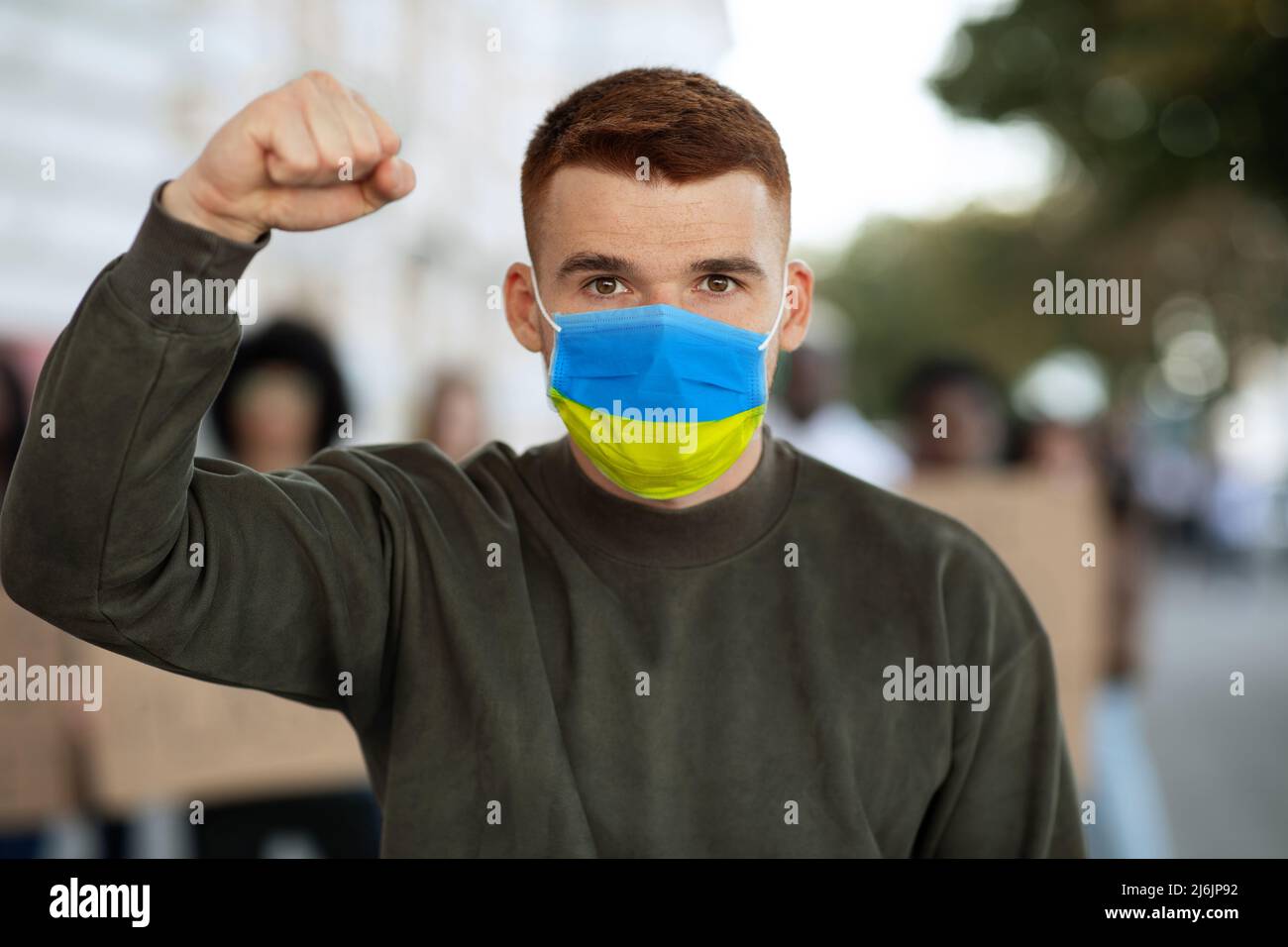 Guy in maschera bandiera Ucraina sopra il gruppo di manifestanti Foto Stock