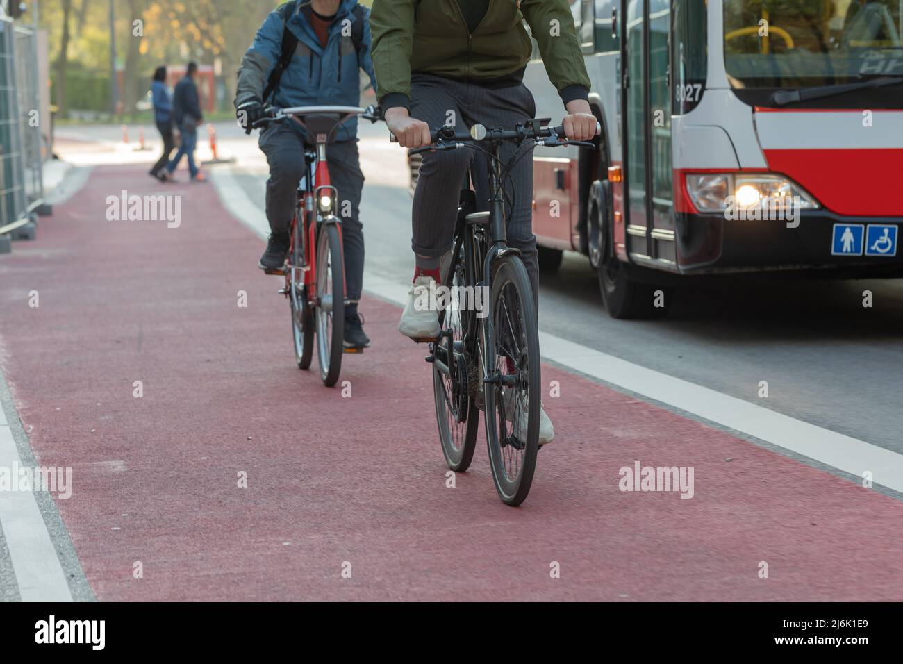 ciclisti sulla pista ciclabile rossa accanto all'autobus cittadino Foto Stock