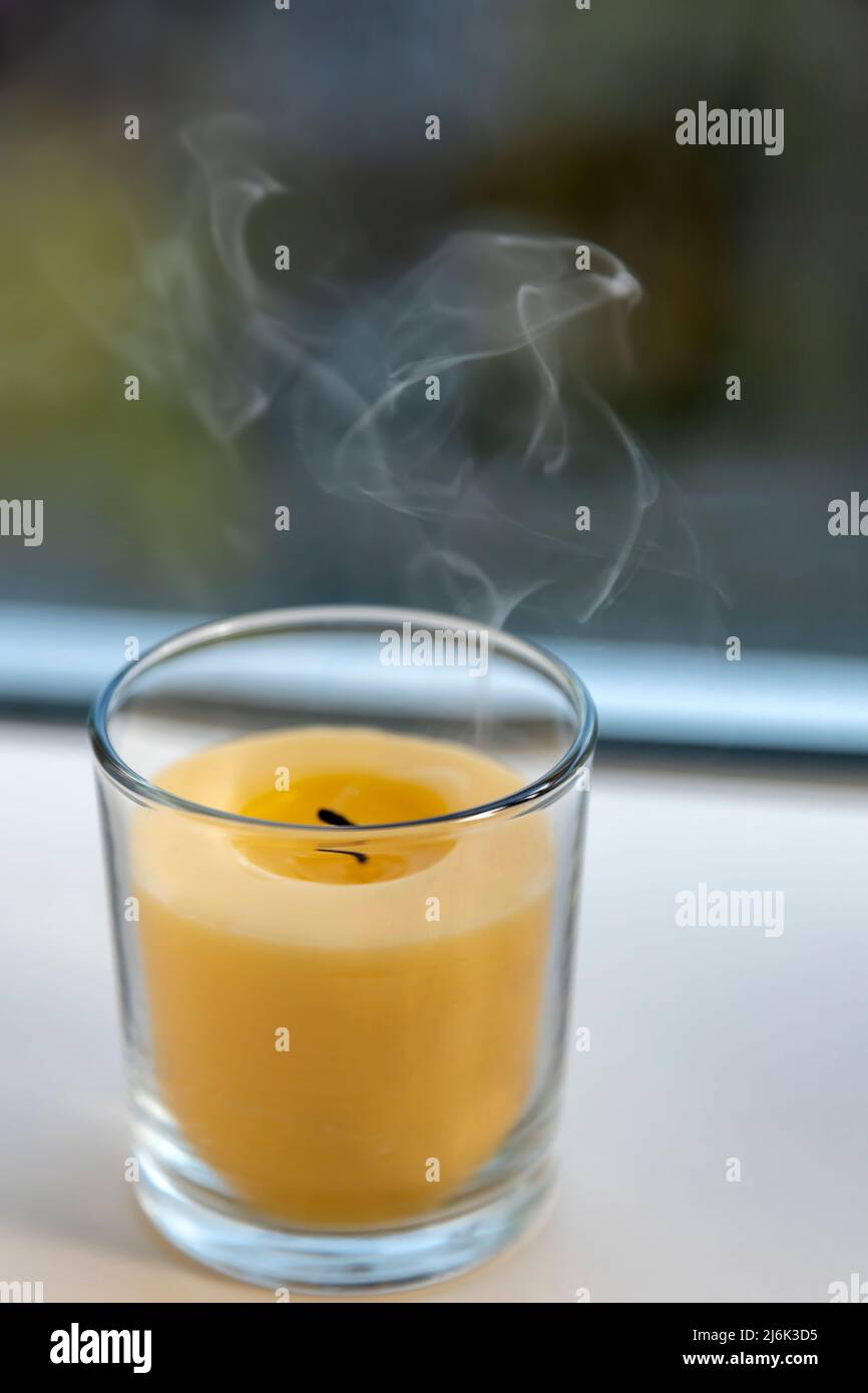 La candela gialla si spegne, il fumo va dallo stoppino alla cima. Foto Stock