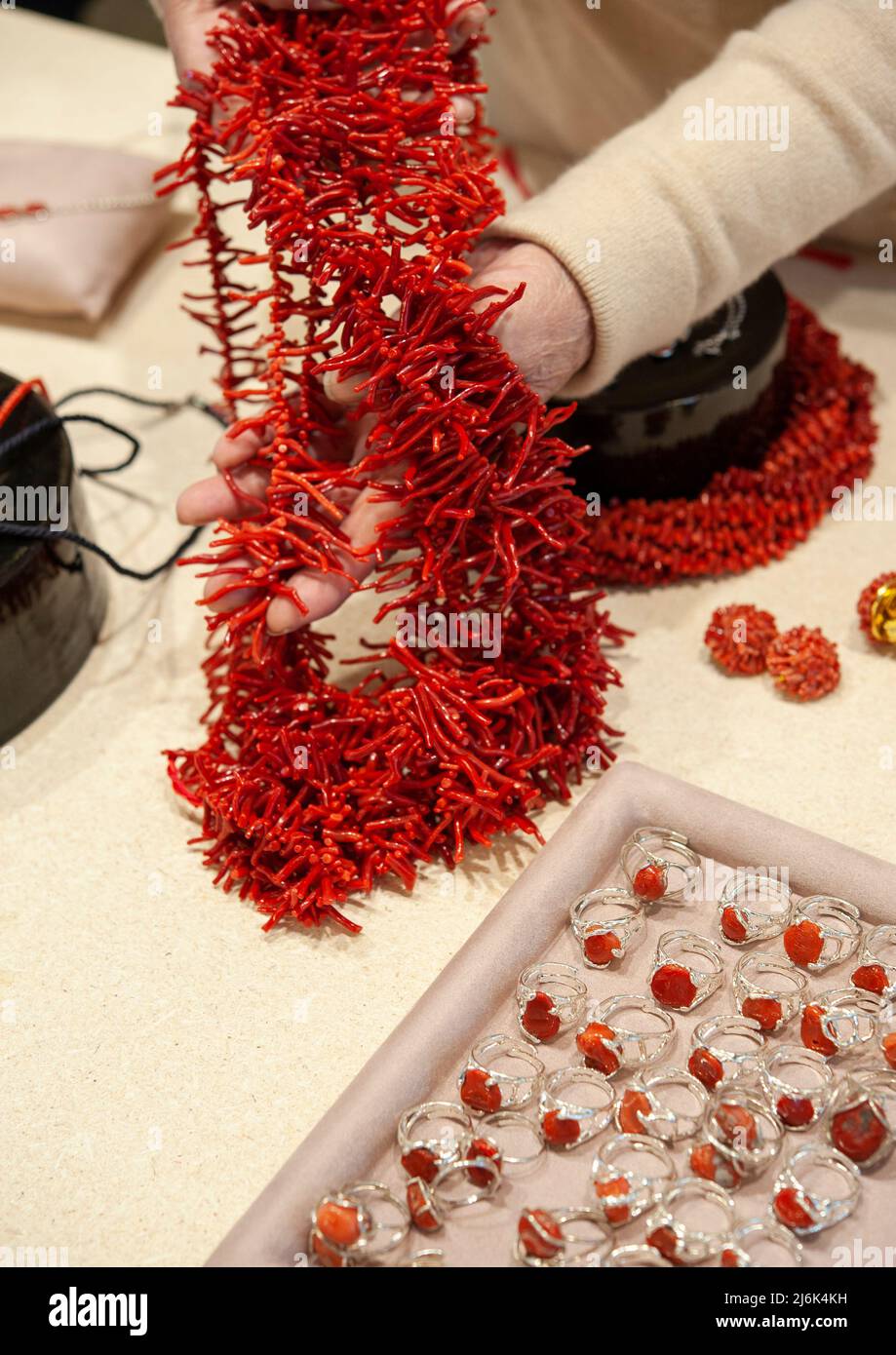 Collana di corallo rosso e anelli d'argento, sul tavolo del gioielliere. Foto Stock