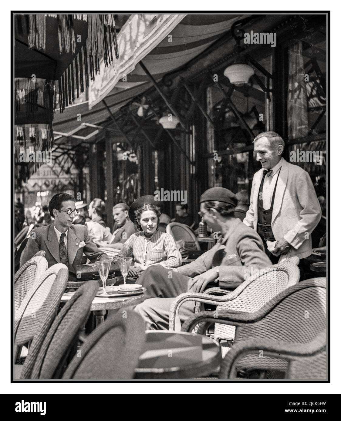 PARIS CAFE RETRO 1940s Post WW2 libertà di guerra ottimismo con gli studenti dell'Università di Parigi (Sorbonne) godere della loro libertà su un elegante caffè parigino all'aperto terrazza ristorante a Parigi, con cameriere parigino tradizionale Data : 1948 Post War luogo : Francia, Parigi fotografo : Willem van de poll Foto Stock